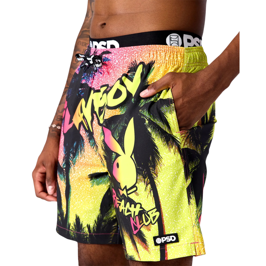 Colorful beach shorts with palm tree design and 'Beach Club' text on a white background