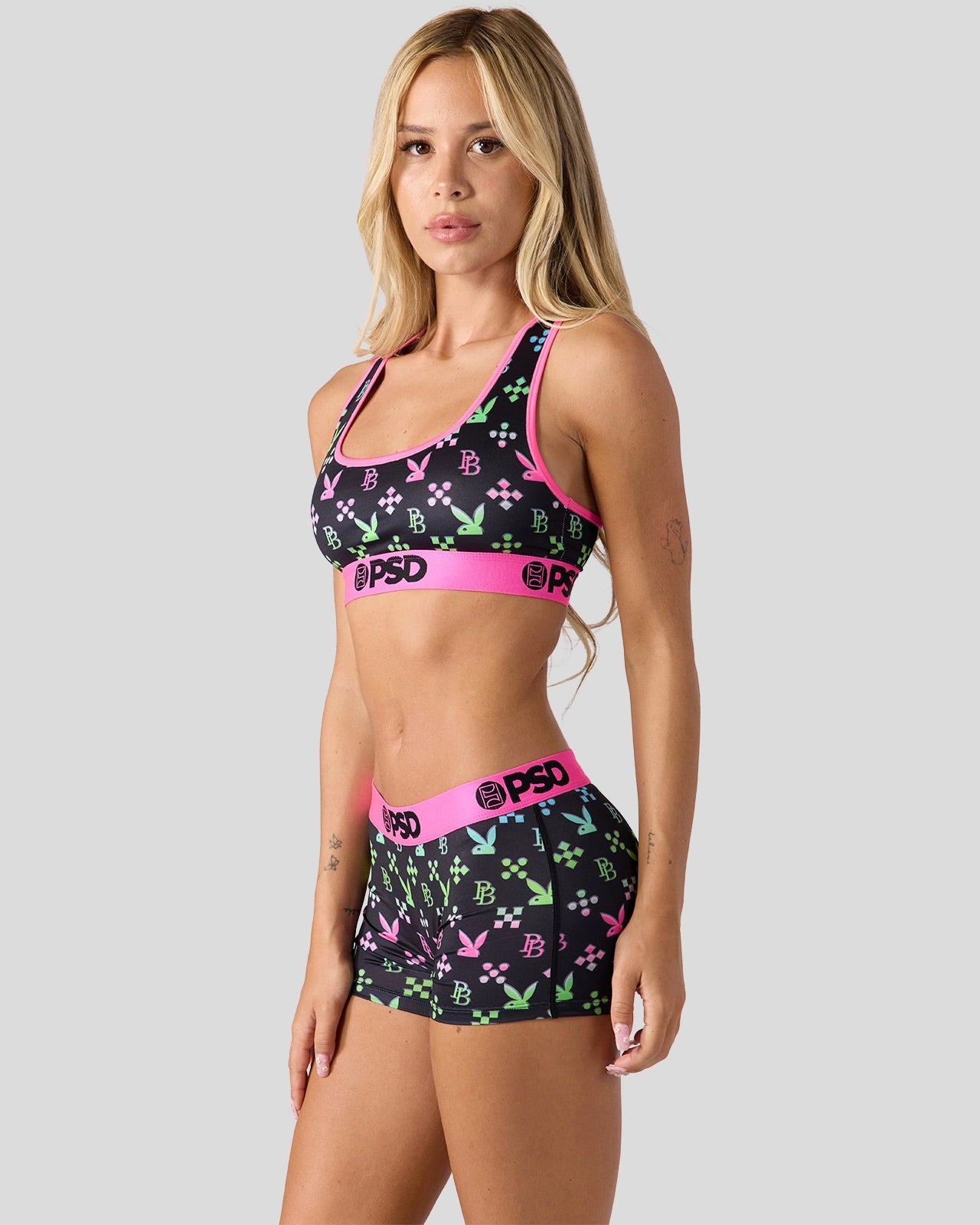 Woman wearing a sports bra and shorts with colorful patterns and 'PSD' branding on a white background