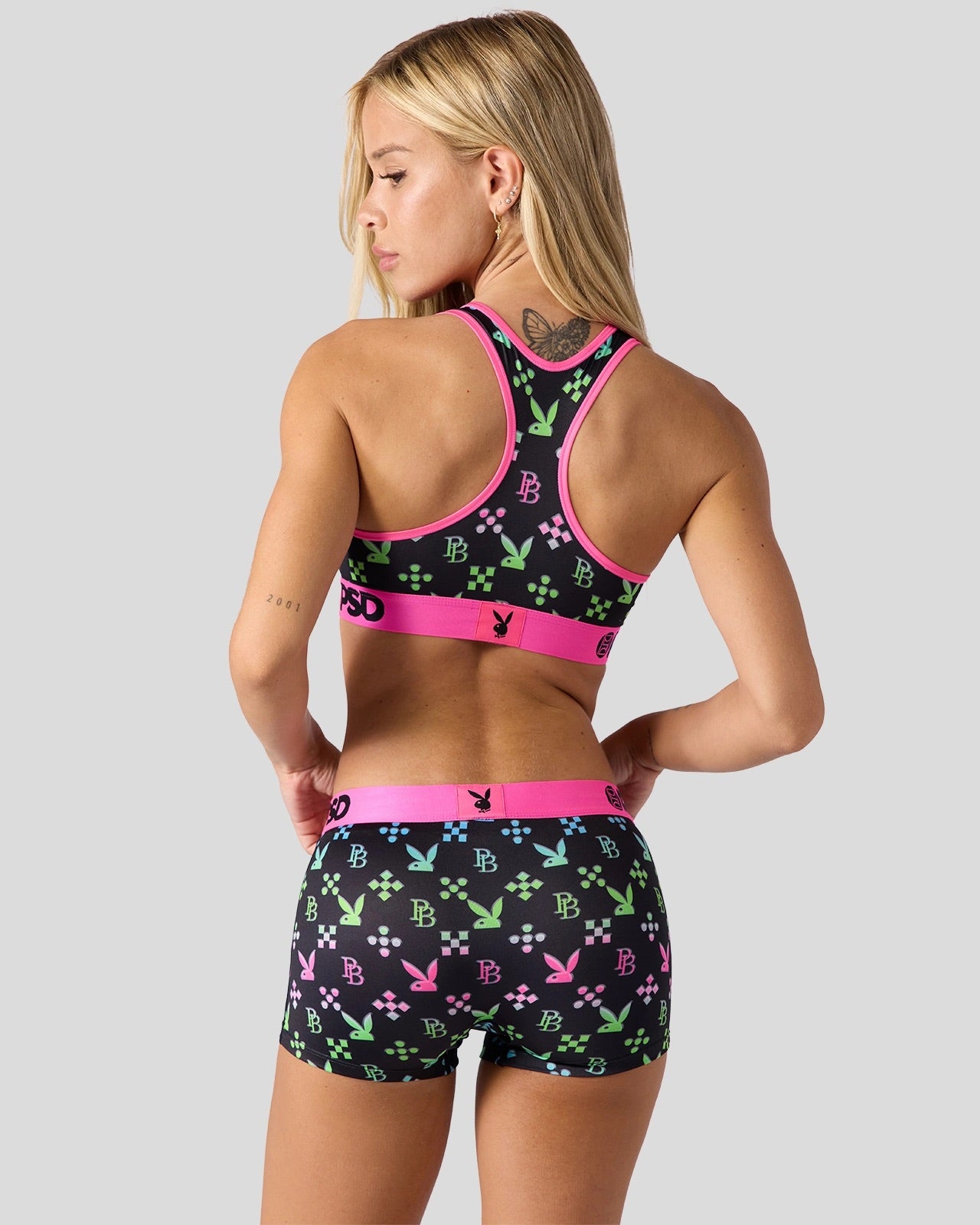 Woman wearing a sports bra and shorts with a colorful pattern on a gray background