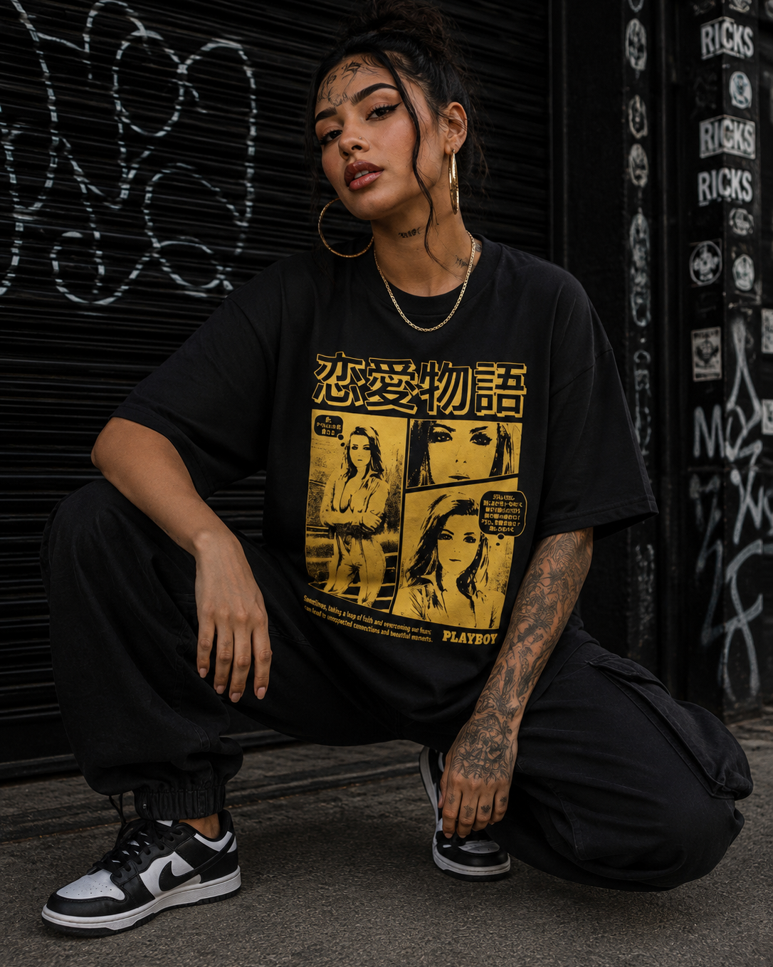 A person crouching in front of a graffiti-covered metal shutter, wearing a black oversized graphic T-shirt with a large yellow retro comic-style print and black cargo pants. #streetwearwomen