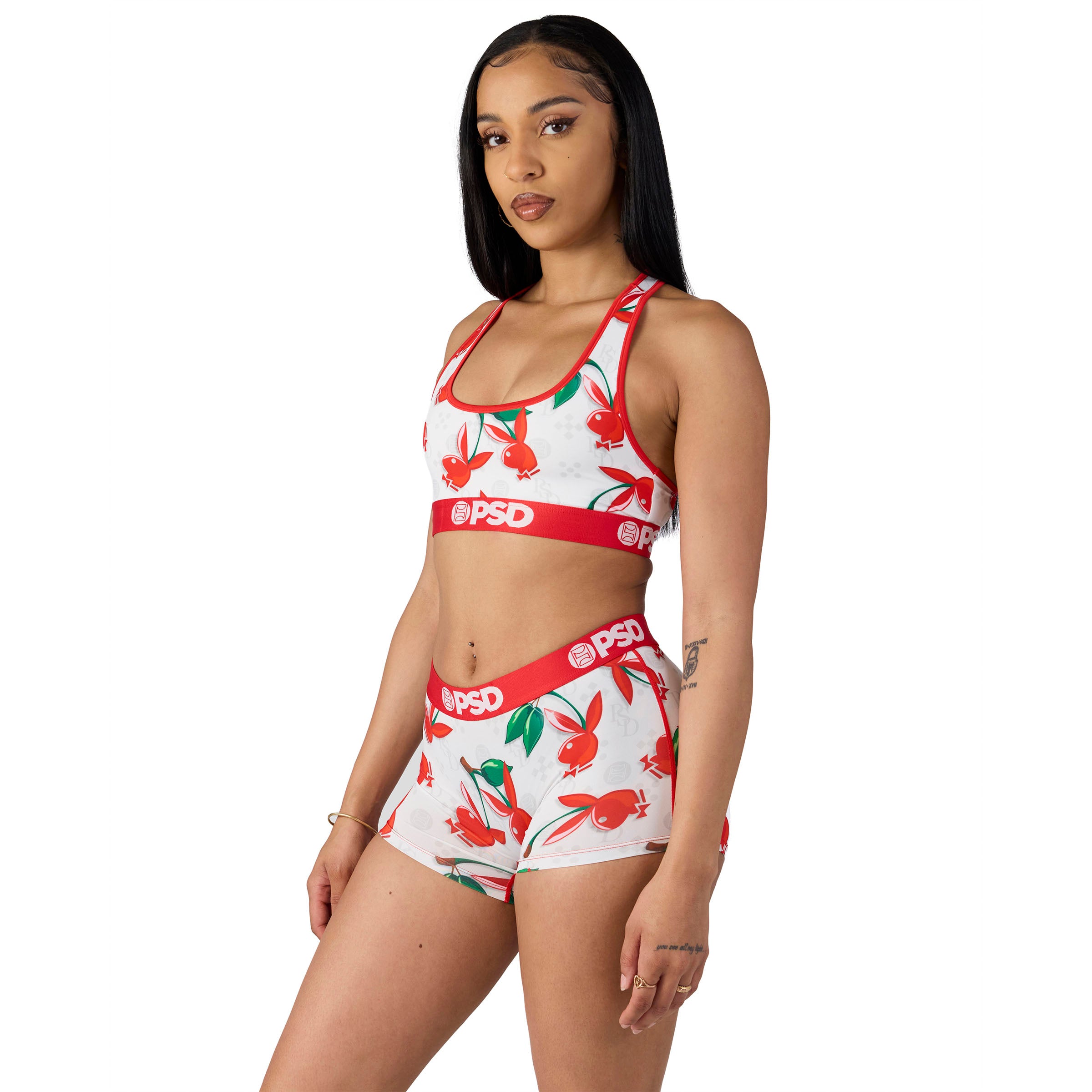 Woman wearing Playboy cherry print sports bra and shorts set with red PSD waistband