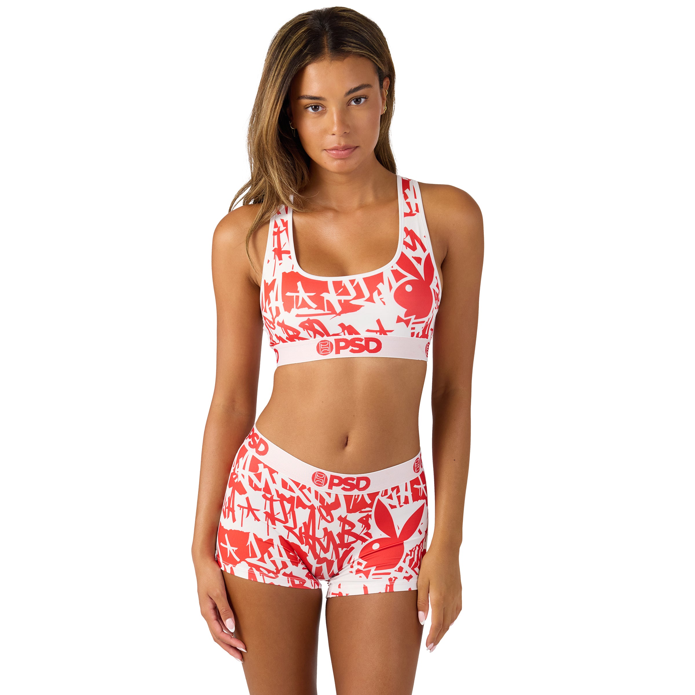Woman wearing red and white Playboy graphic sports bra and shorts set by PSD, isolated on white