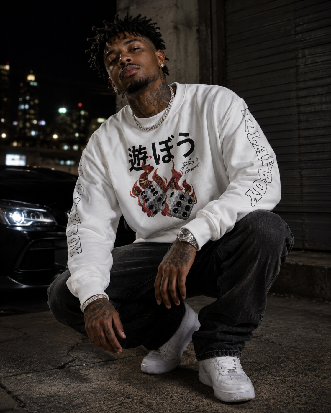 A man crouching at night wearing a white crewneck sweatshirt with a black and red graphic print featuring Japanese characters and dice, paired with black jeans and white sneakers. #Streetwearmen