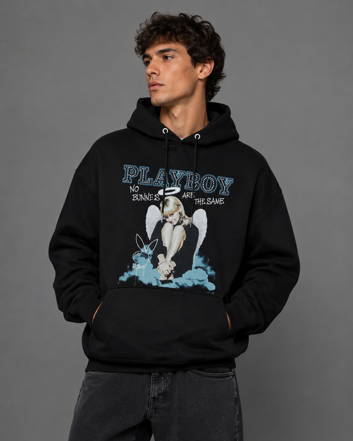 A man wearing a black Playboy hoodie with a graphic print of a winged bunny and the text 'No Bunnies Are The Same', posed against a solid gray studio background.