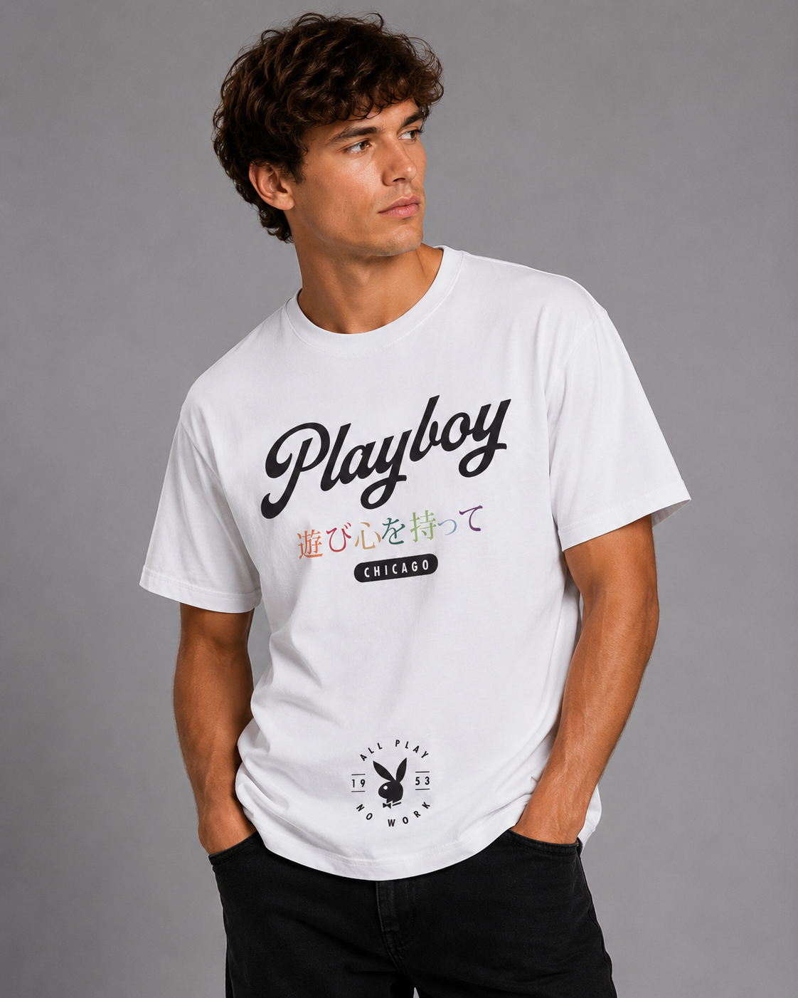 A man wearing a white Playboy t-shirt with black script lettering and Japanese text, paired with black pants, against a solid gray studio background.