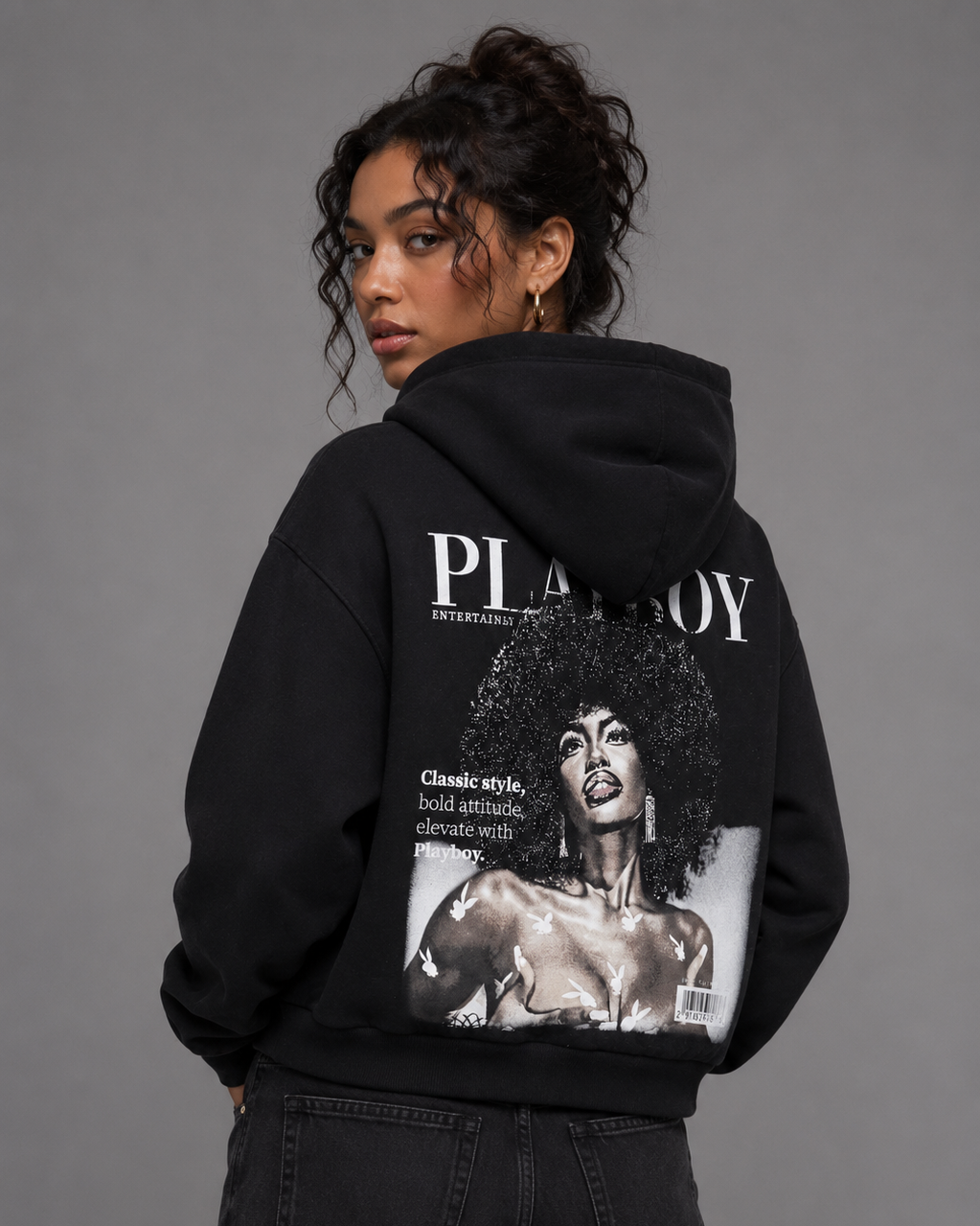A model shown from the back wearing a black hoodie with a large vintage Playboy magazine cover graphic on the back, paired with black jeans, against a solid gray studio background. #Women