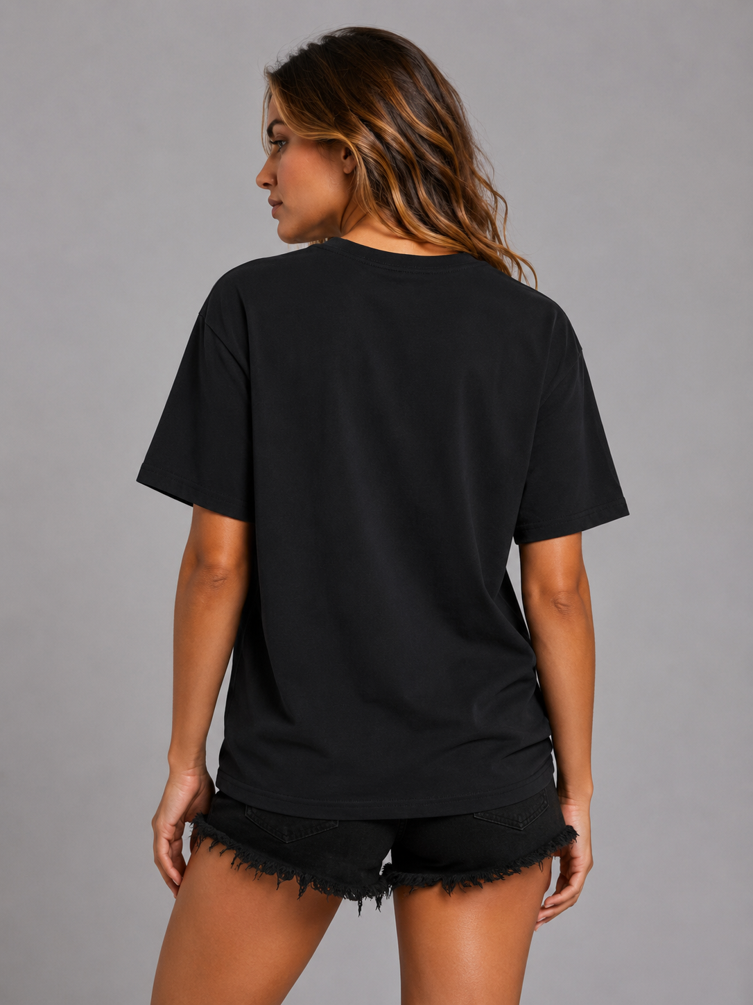 A woman shown from the back wearing a plain black short-sleeve T-shirt and black frayed denim shorts against a solid gray studio background. #Women