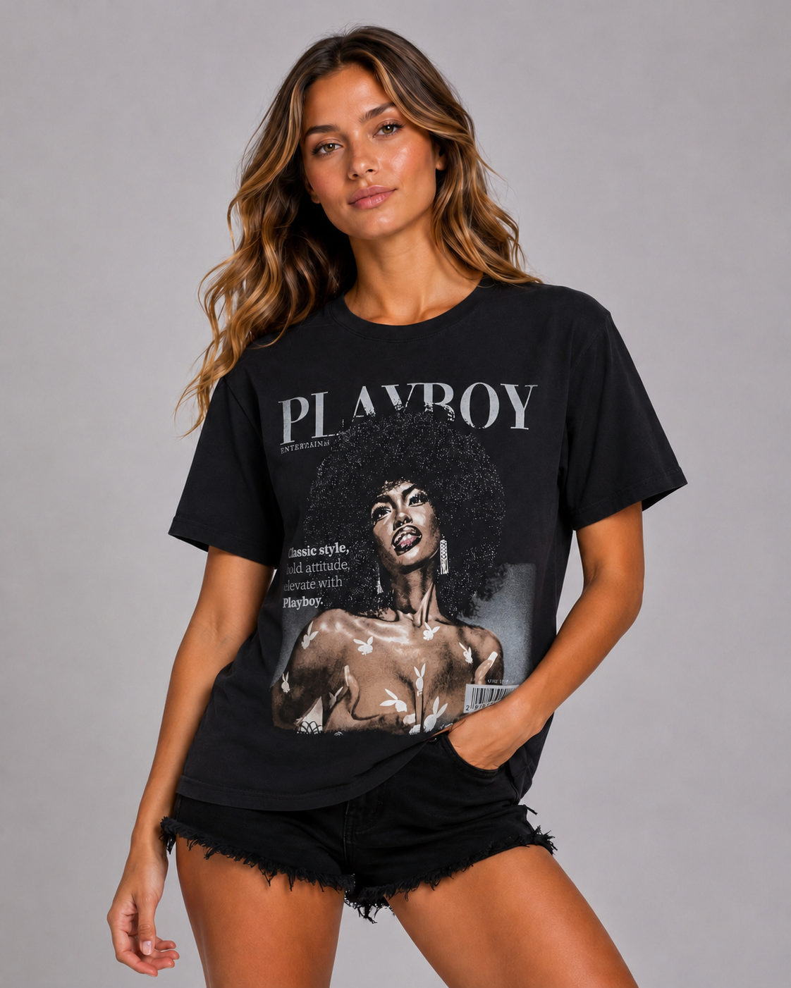 A woman modeling a black Playboy t-shirt with a large vintage-style graphic print on the front, paired with black denim shorts, against a solid gray studio background. #Women