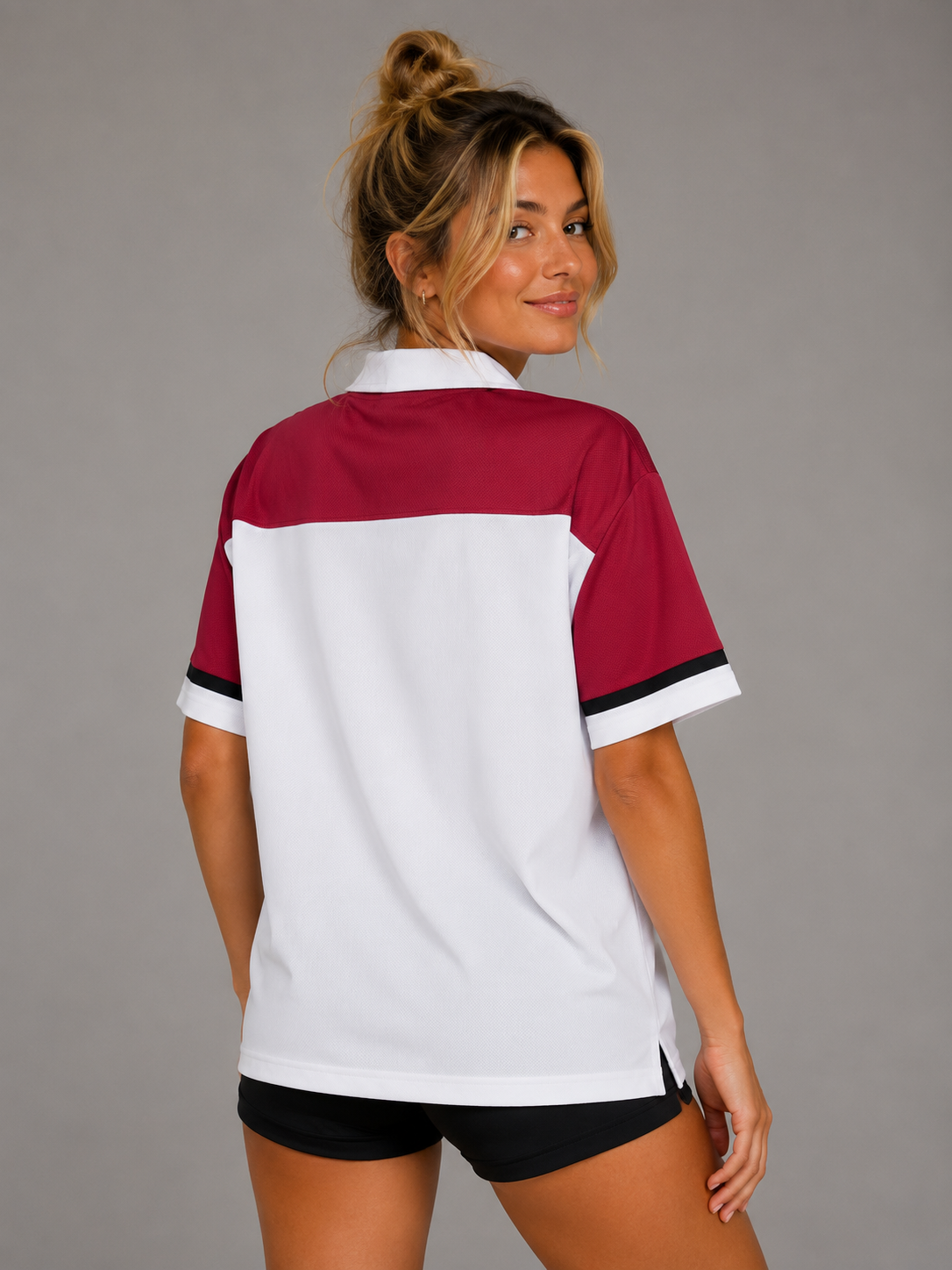 A woman wearing a short-sleeve colorblock polo shirt with a burgundy upper section, white lower section, and black trim on the sleeve cuffs, shown from the back against a solid gray studio background. #Women