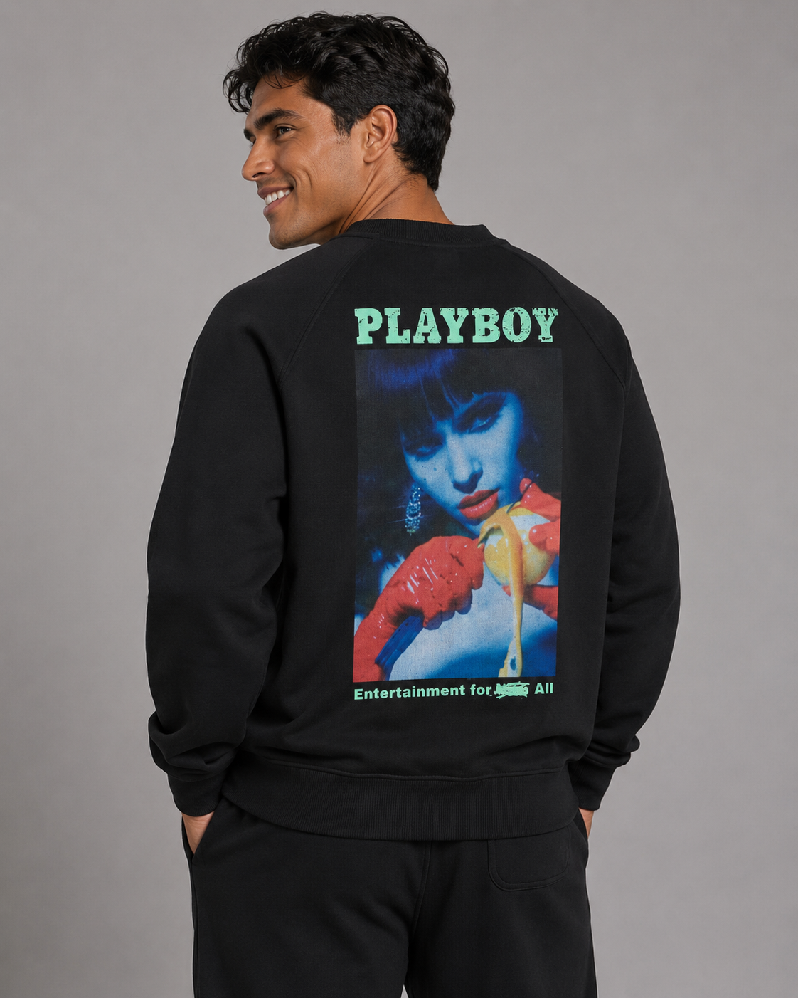 A man wearing a black sweatshirt, shown from the back, featuring a large graphic print of a woman with a cocktail and the word 'PLAYBOY' in green text.