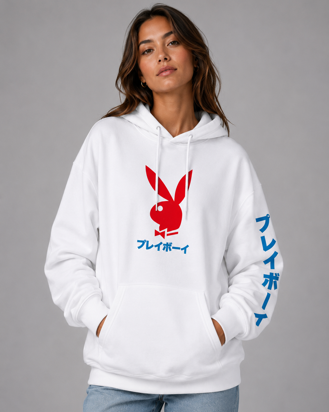 A woman wearing a white pullover hoodie with a red Playboy bunny logo and blue Japanese text on the front and sleeve, paired with light blue jeans, against a solid gray studio background. #Women