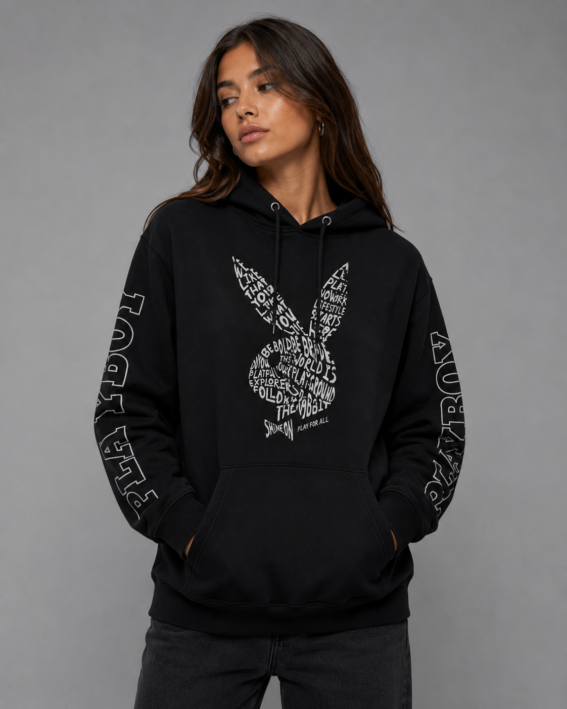 A woman modeling a black pullover hoodie with a large white typographic bunny graphic on the front and white text running down both sleeves, photographed against a plain gray studio background. #Women