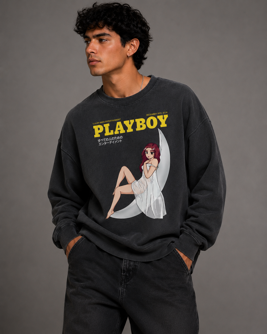 A man wearing a dark charcoal gray crewneck sweatshirt featuring a yellow 'PLAYBOY' logo and a retro pin-up illustration on the front, paired with black jeans against a solid gray studio background. #Streetwearmen