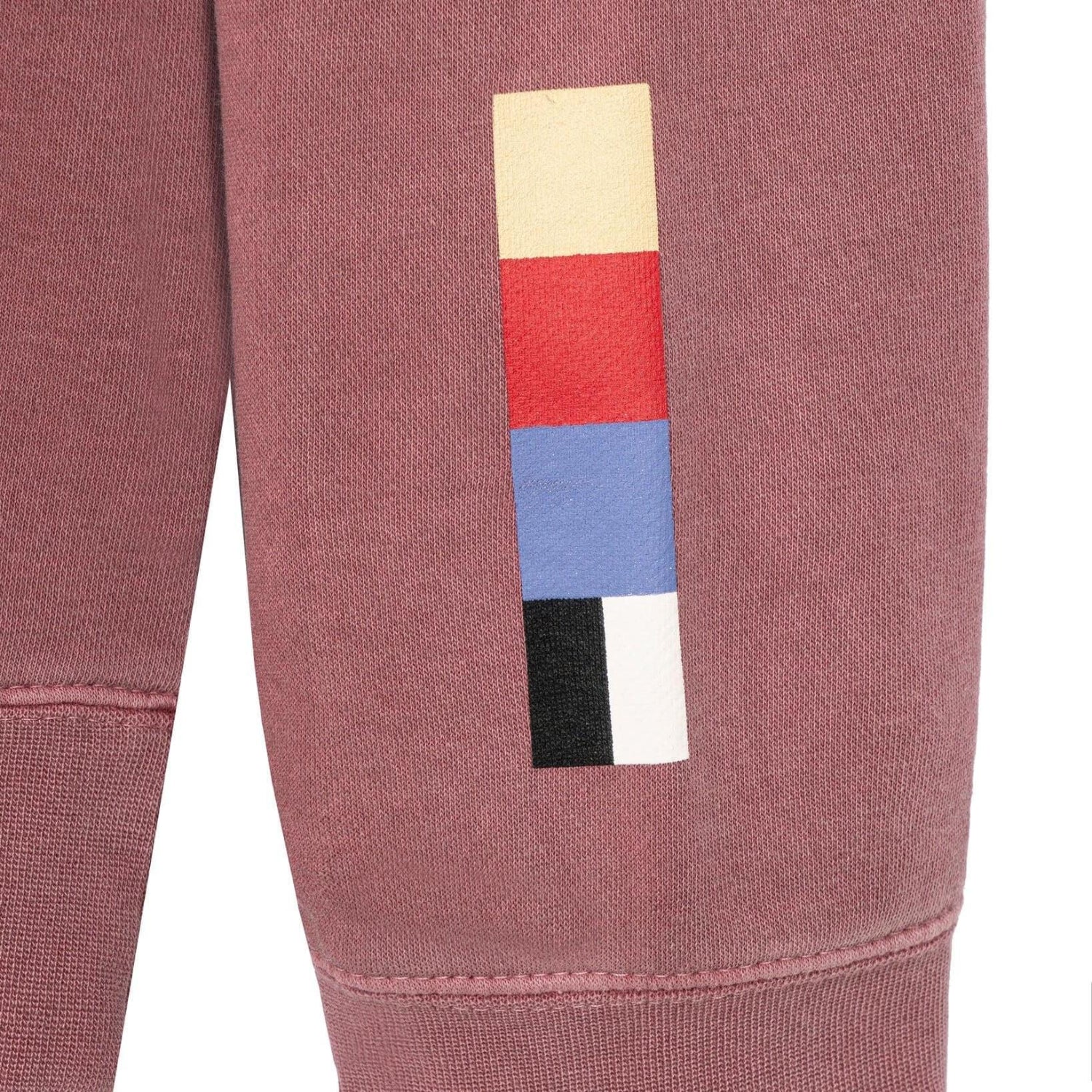 Close-up of mauve crewneck sweatshirt sleeve with yellow, red, blue, black, and white graphic blocks