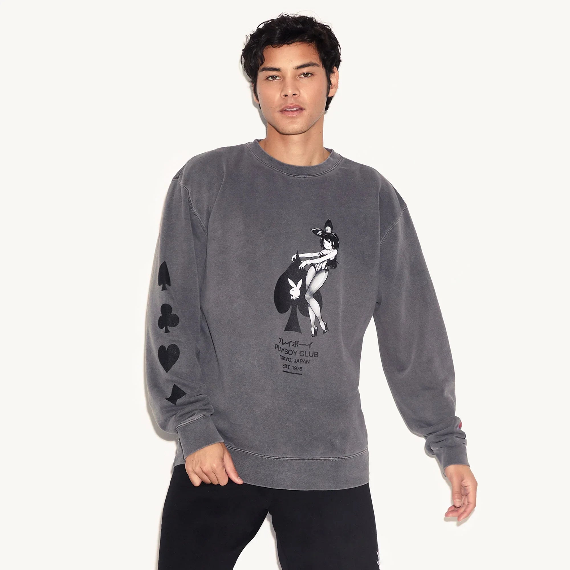 Man wearing charcoal crewneck sweatshirt with ace of spades and bunny graphic, card suit sleeves.