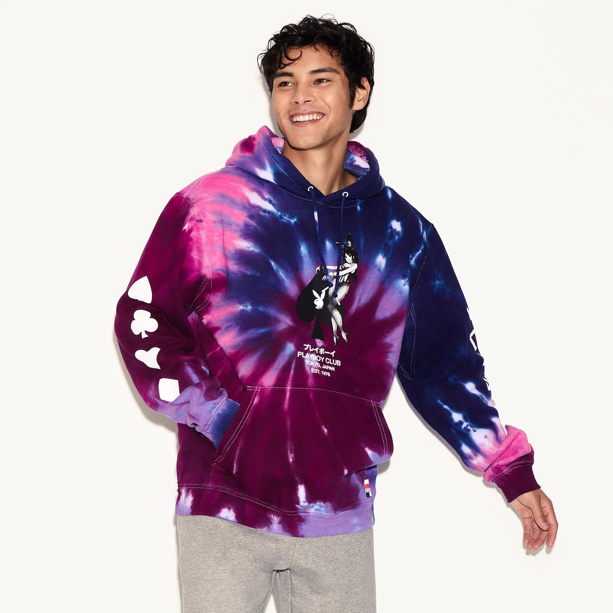 Man wearing purple and blue tie-dye hoodie with ace of spades and cartoon graphic on front
