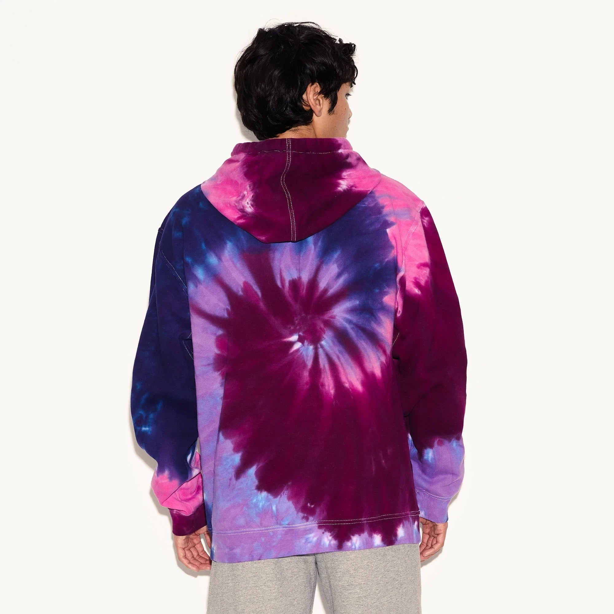 Man wearing a purple and blue tie-dye hoodie with spiral pattern, seen from the back.