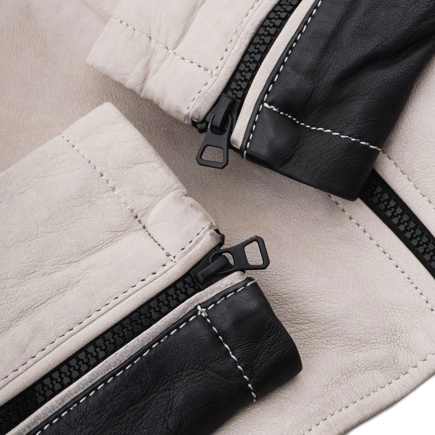 Close-up of cream and black leather jacket sleeves with visible zippers and stitching detail