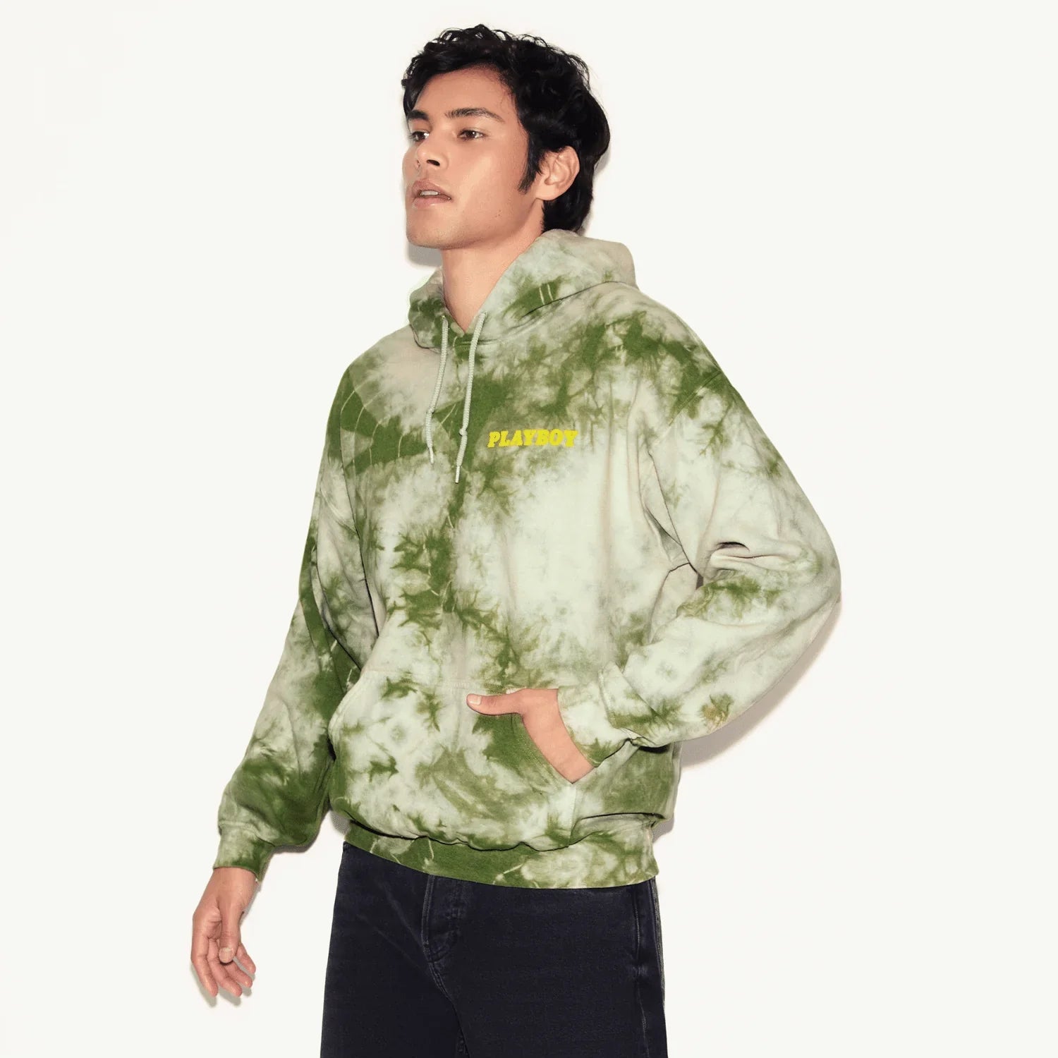 Man wearing green tie-dye hoodie with yellow Playboy logo, casual streetwear style