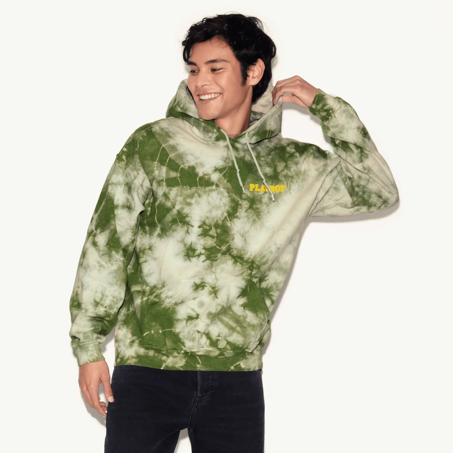 Man wearing a green tie-dye hoodie with yellow embroidered text, casual streetwear style