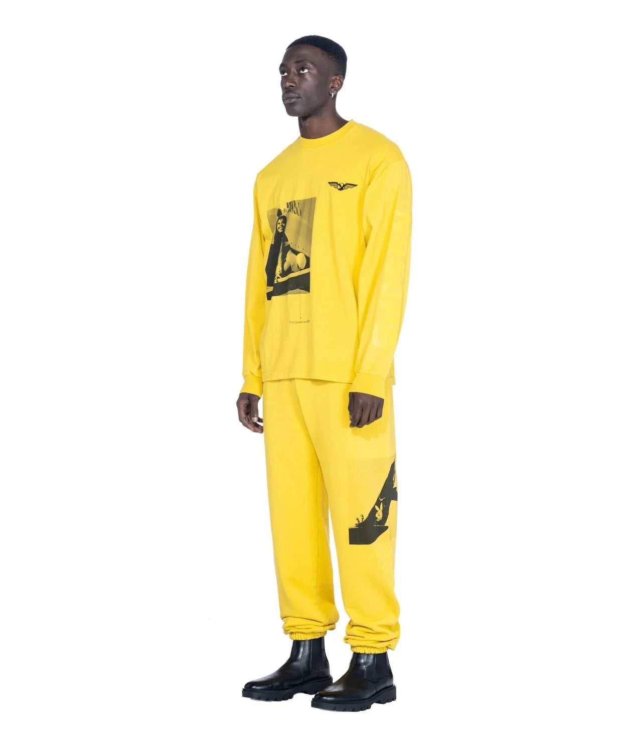 Man wearing yellow graphic long sleeve shirt and matching sweatpants with black ankle boots