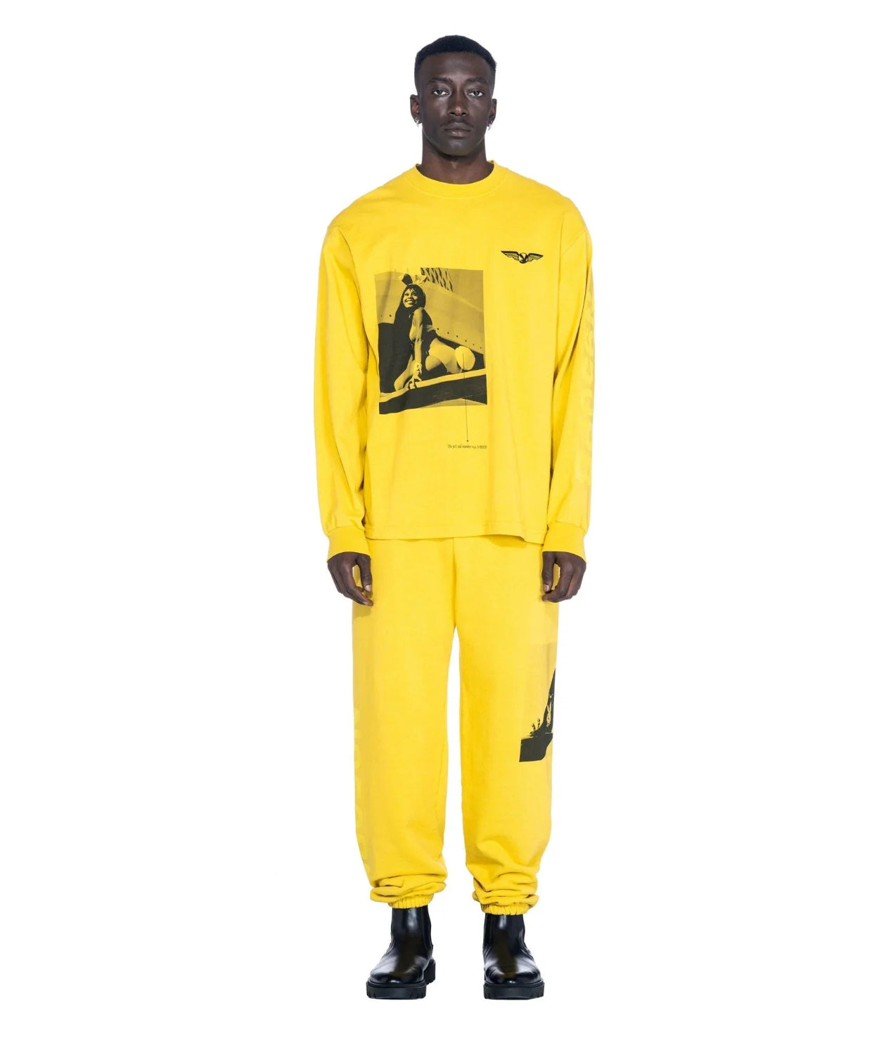 Man wearing yellow long sleeve graphic t-shirt and matching pants with black boots