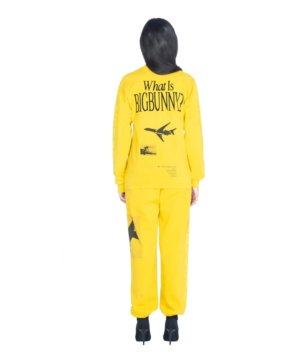 Woman in yellow long sleeve shirt and pants with 'What Is BigBunny?' and airplane graphic on back.
