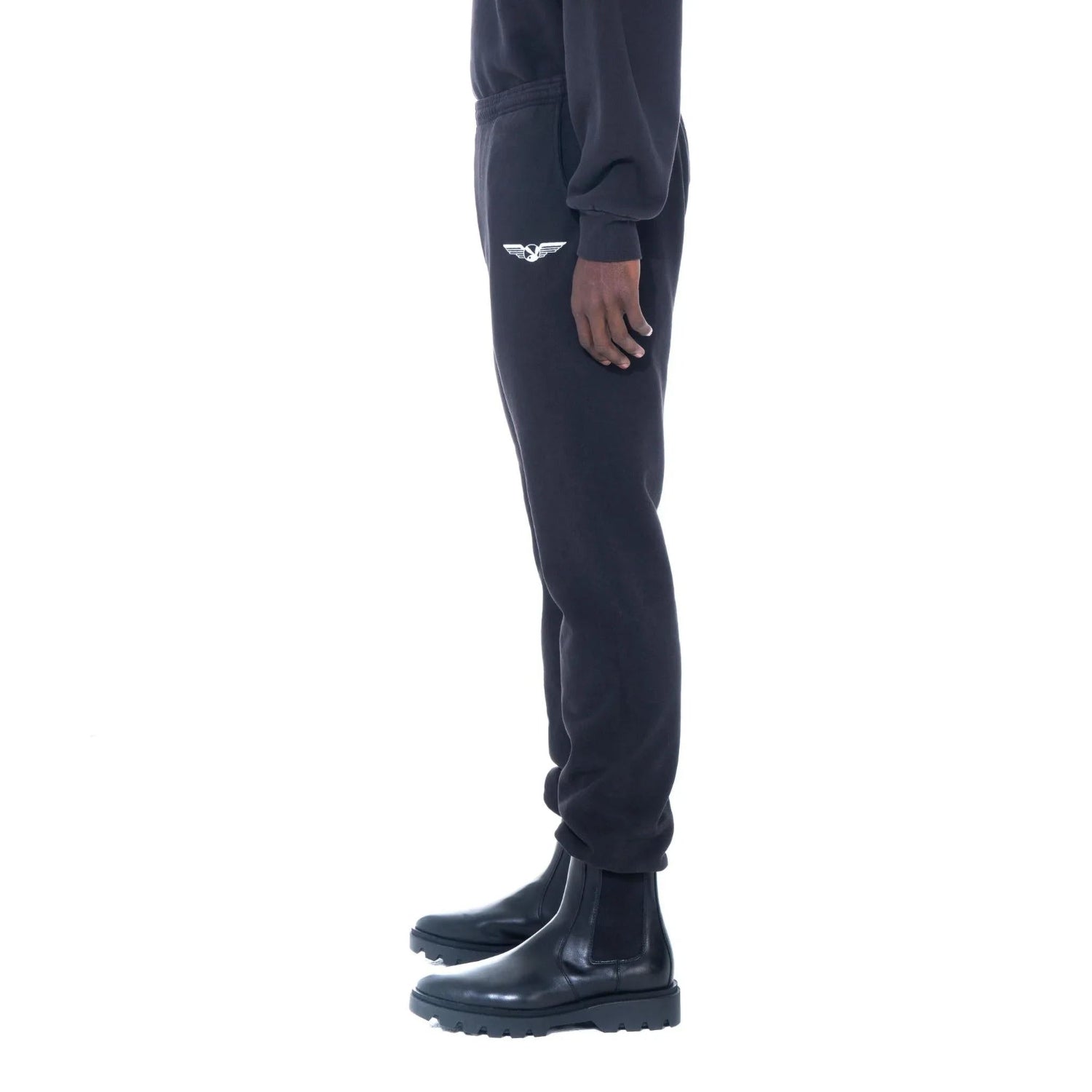 Black sweatpants with embroidered aviation wings logo on hip, worn with black boots