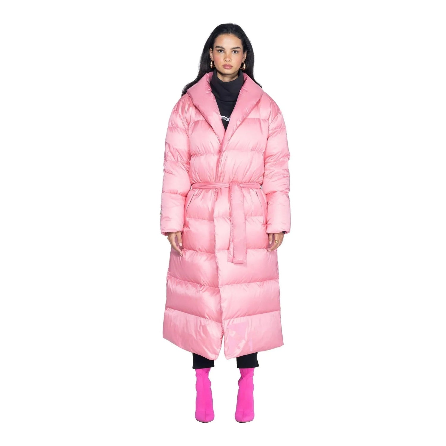 Woman wearing a pink belted long puffer jacket and matching pink boots, front view