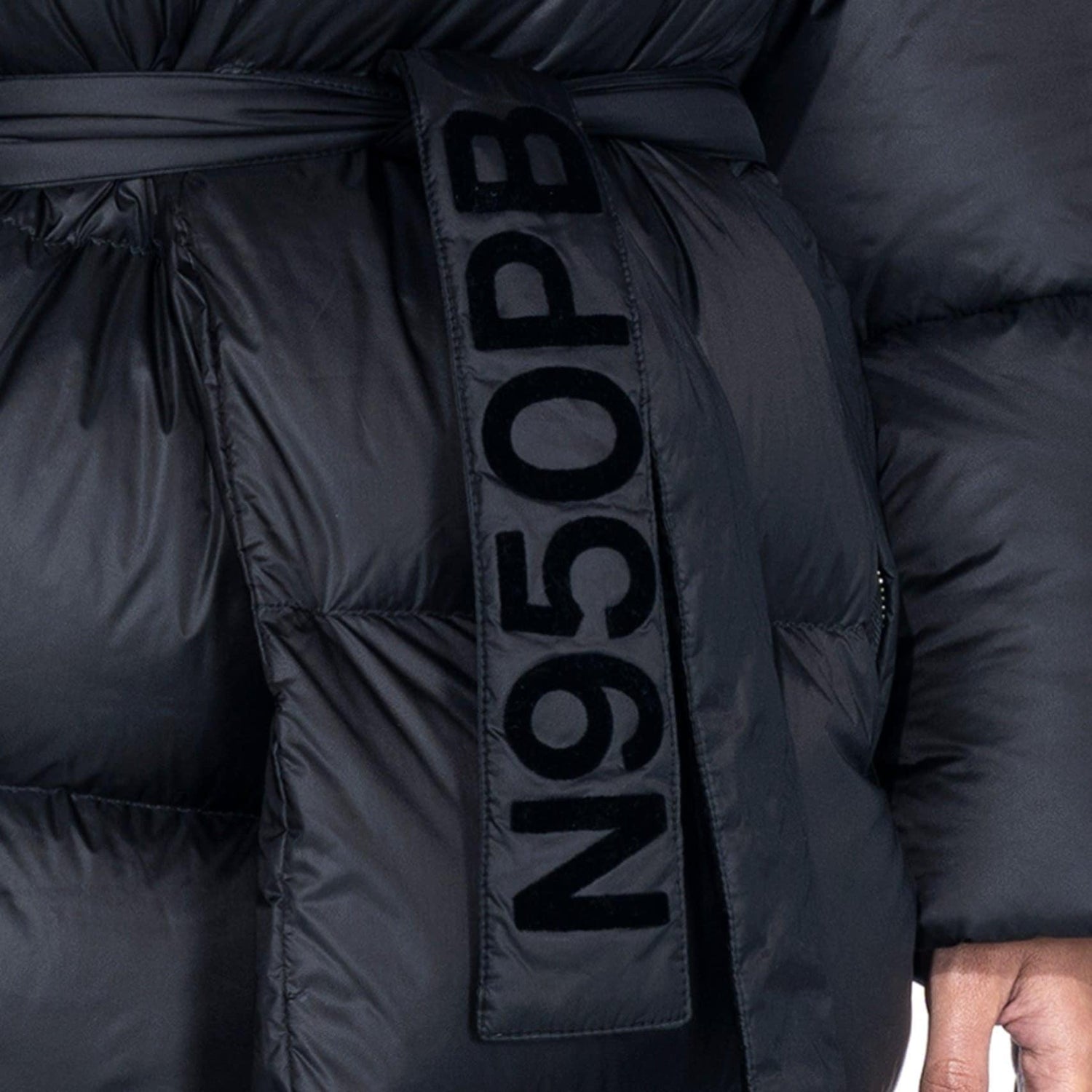 Close-up of black belted long puffer jacket with N950PB lettering on belt