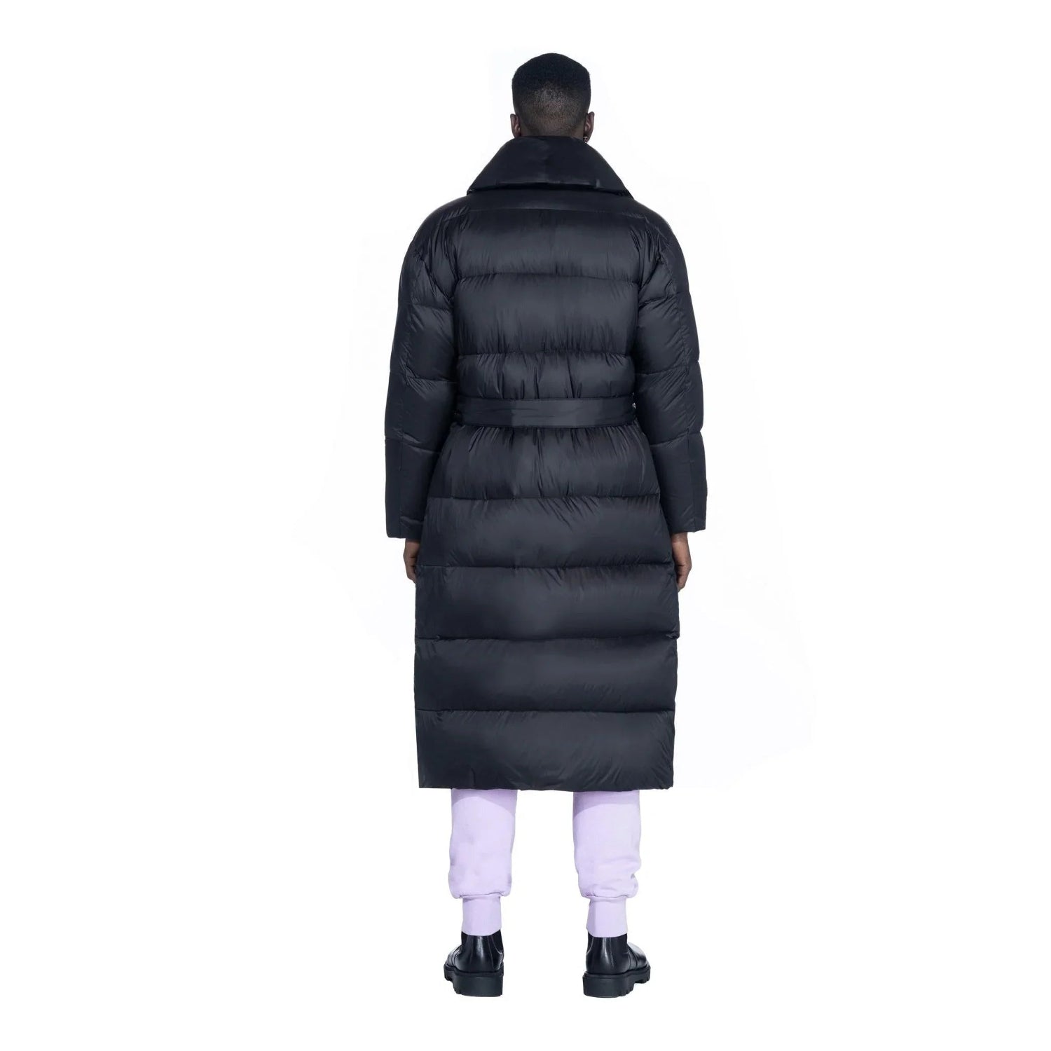 Back view of a person wearing a black belted long puffer jacket and light pants