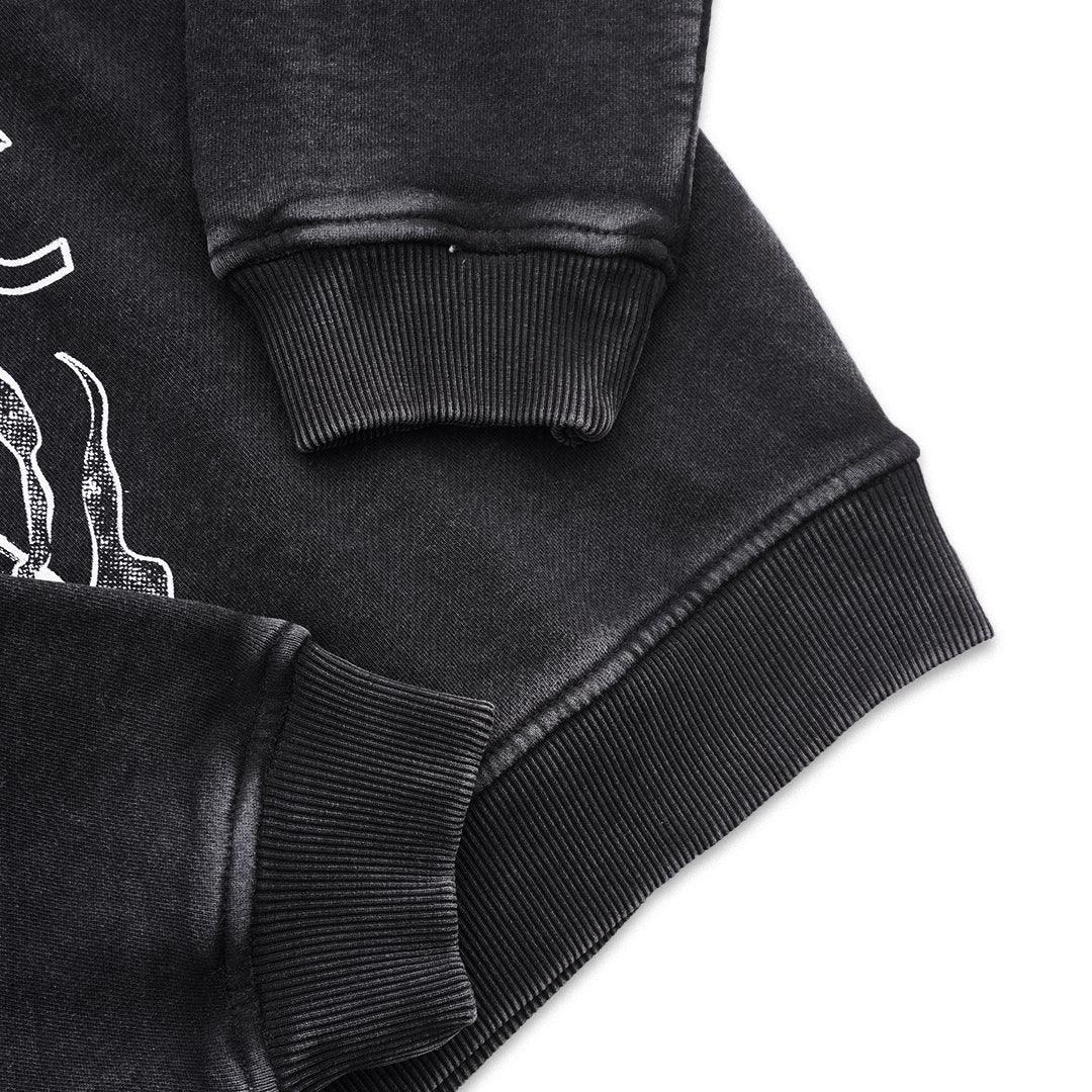 Black sweatshirt close-up with ribbed cuffs, partial white graphic print on sleeve