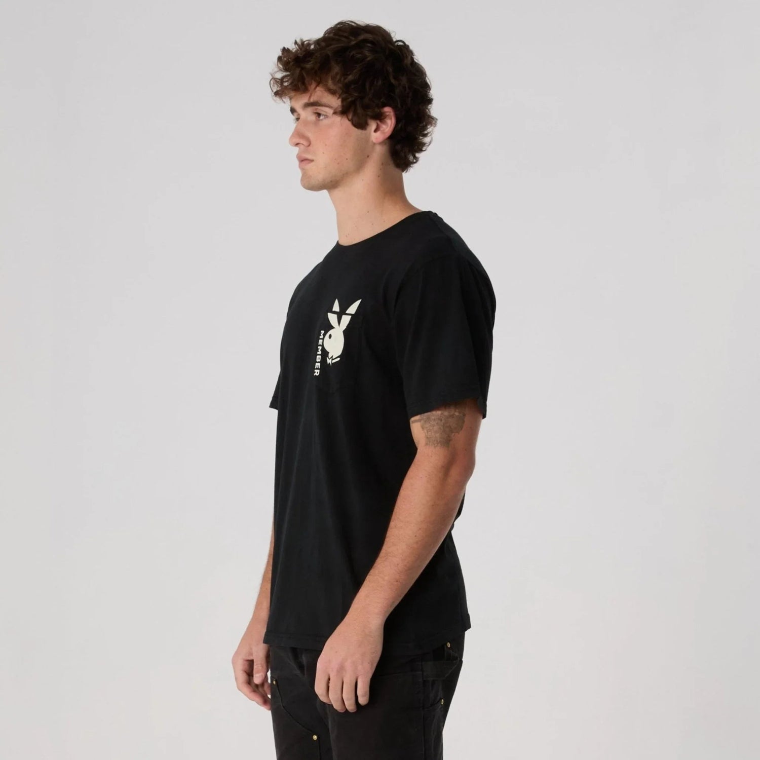Man wearing black pocket tee with white bunny logo and text graphic on chest