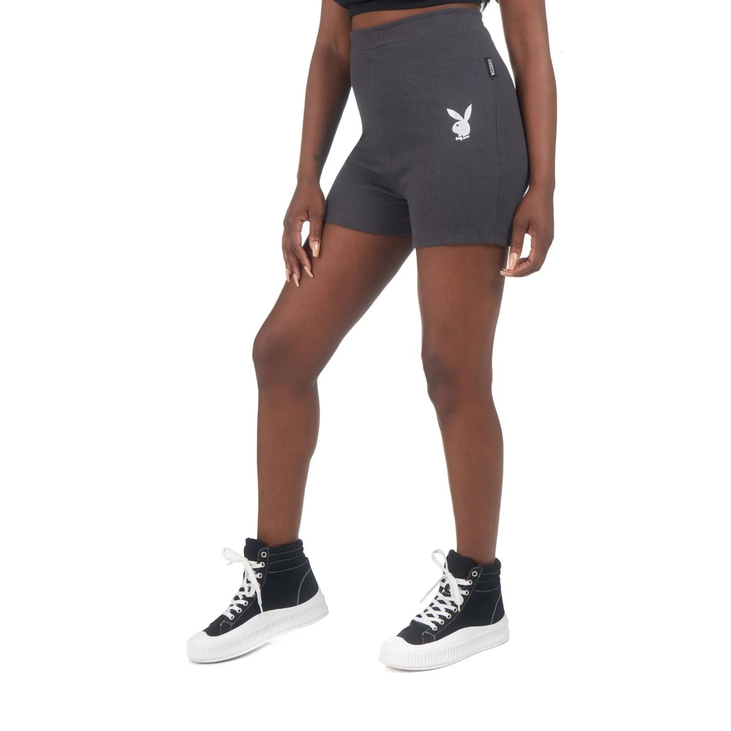 Woman wearing black high-waisted biking shorts with white bunny logo and black sneakers