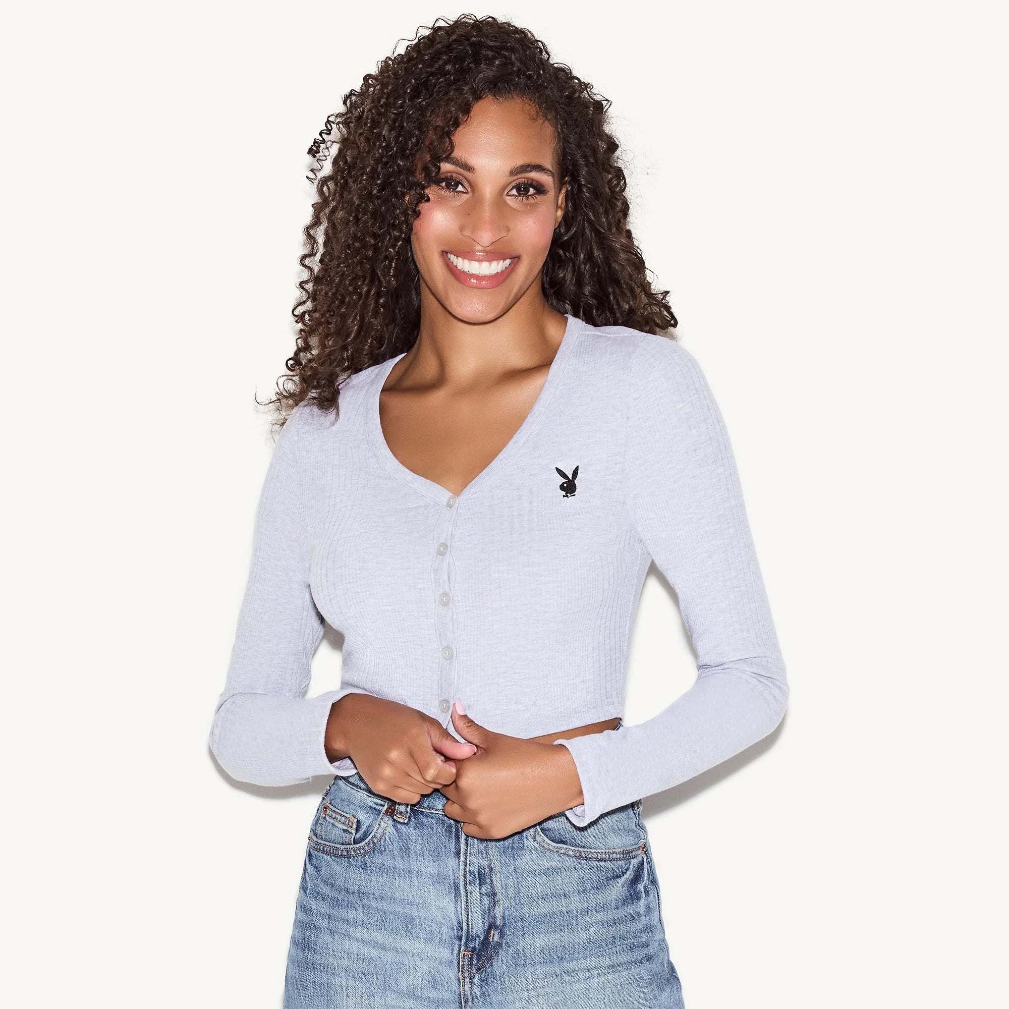Woman wearing light gray ribbed button-up cardigan with iconic bunny head logo, blue jeans