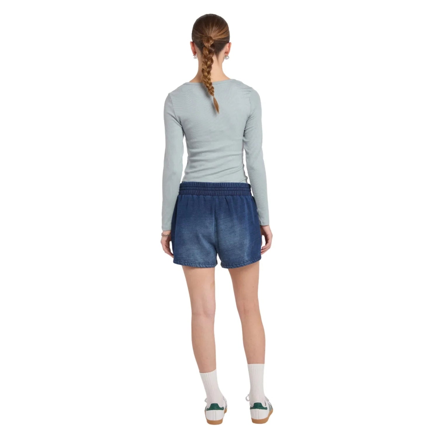 Woman wearing denim shorts with elastic waistband, long sleeve top, white socks, green sneakers