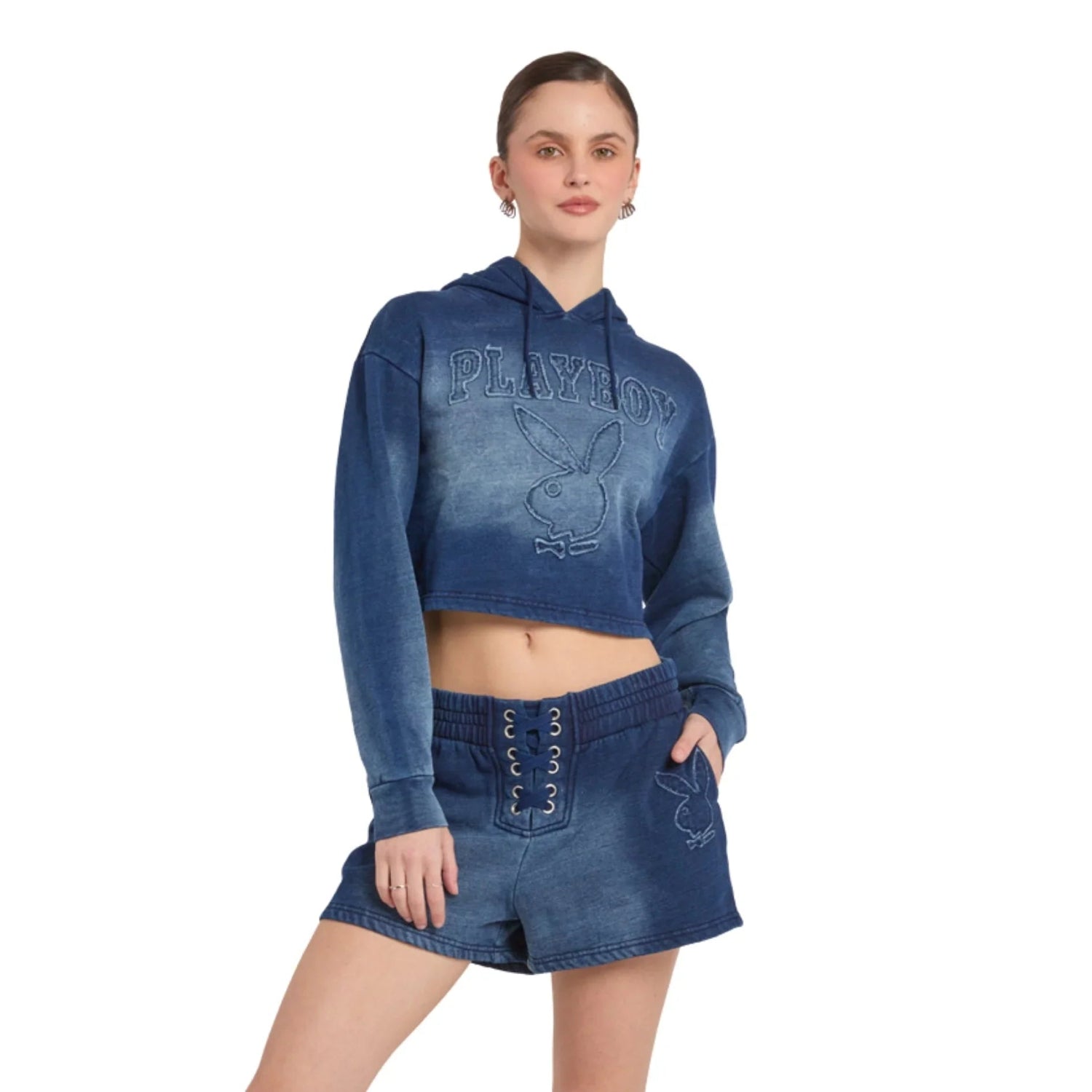 Woman wearing blue hooded crop top with logo and matching lace-up denim shorts
