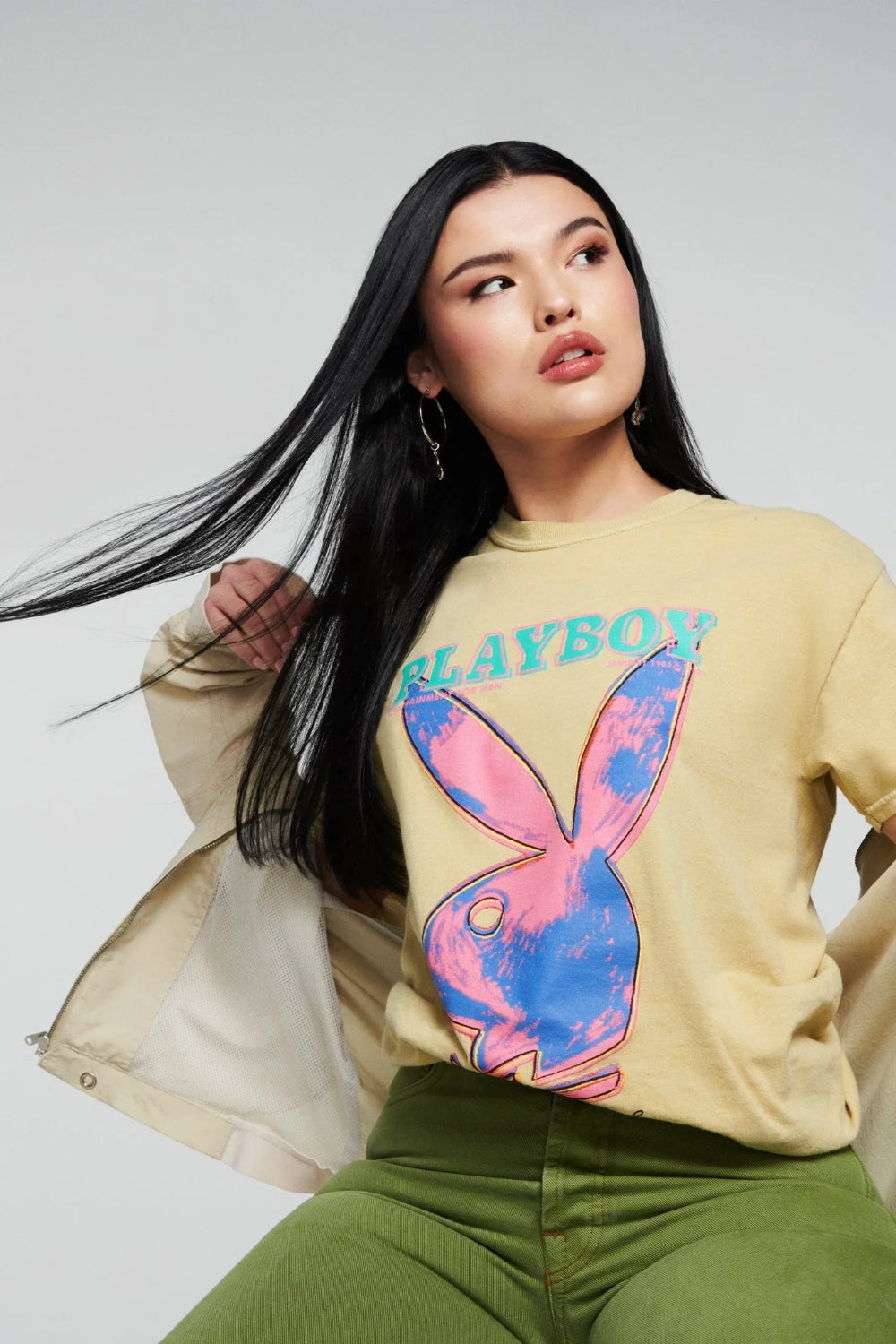 Woman in yellow pop art graphic t-shirt with colorful bunny logo and green pants