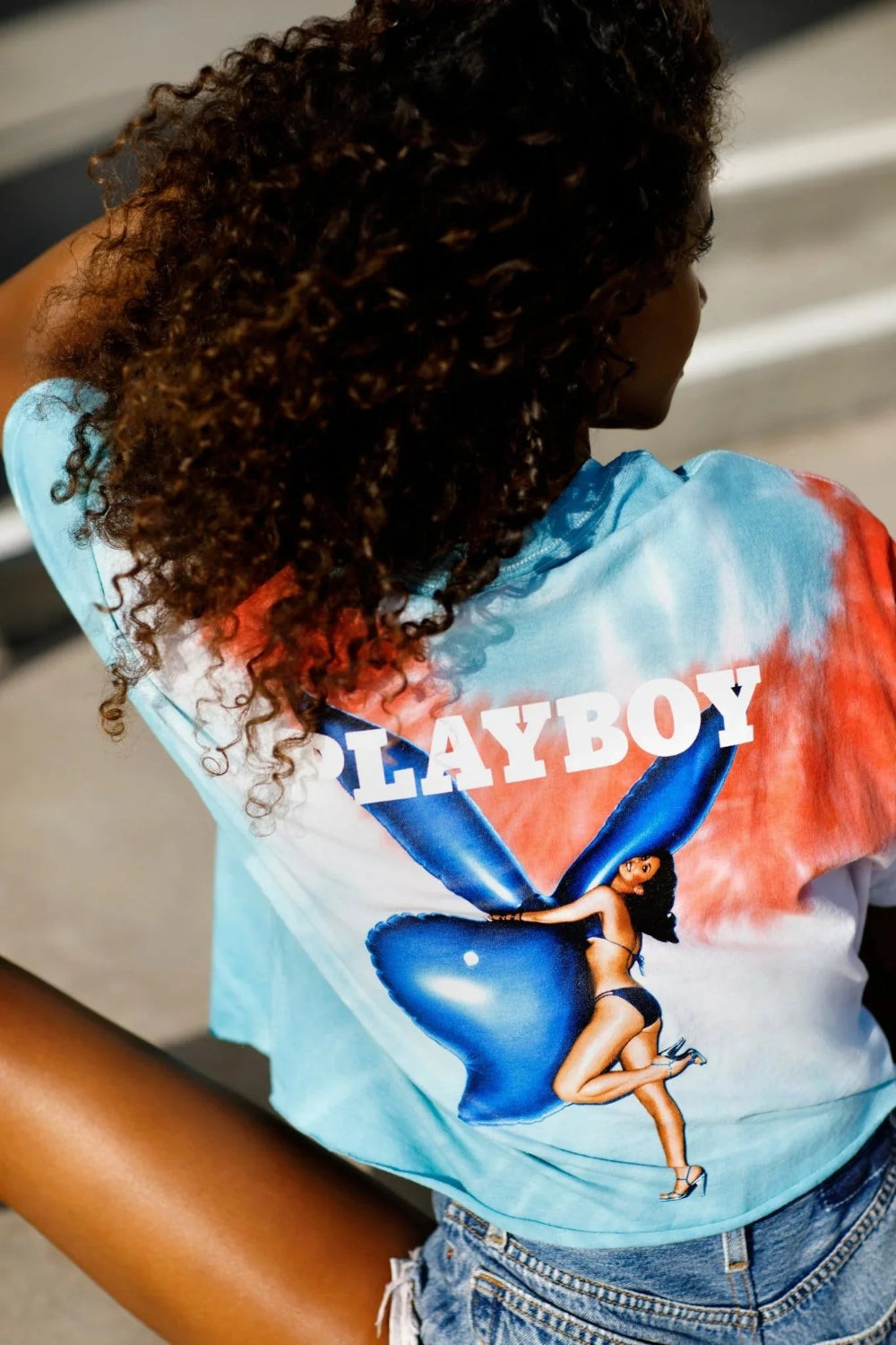 Woman wearing tie-dye crop t-shirt with retro graphic and denim shorts outdoors