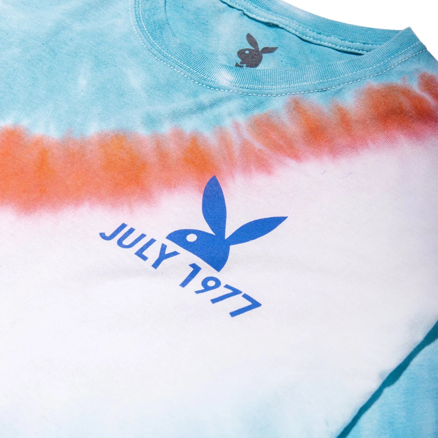Tie-dye crop t-shirt with blue bunny logo and July 1977 text, orange and teal pattern