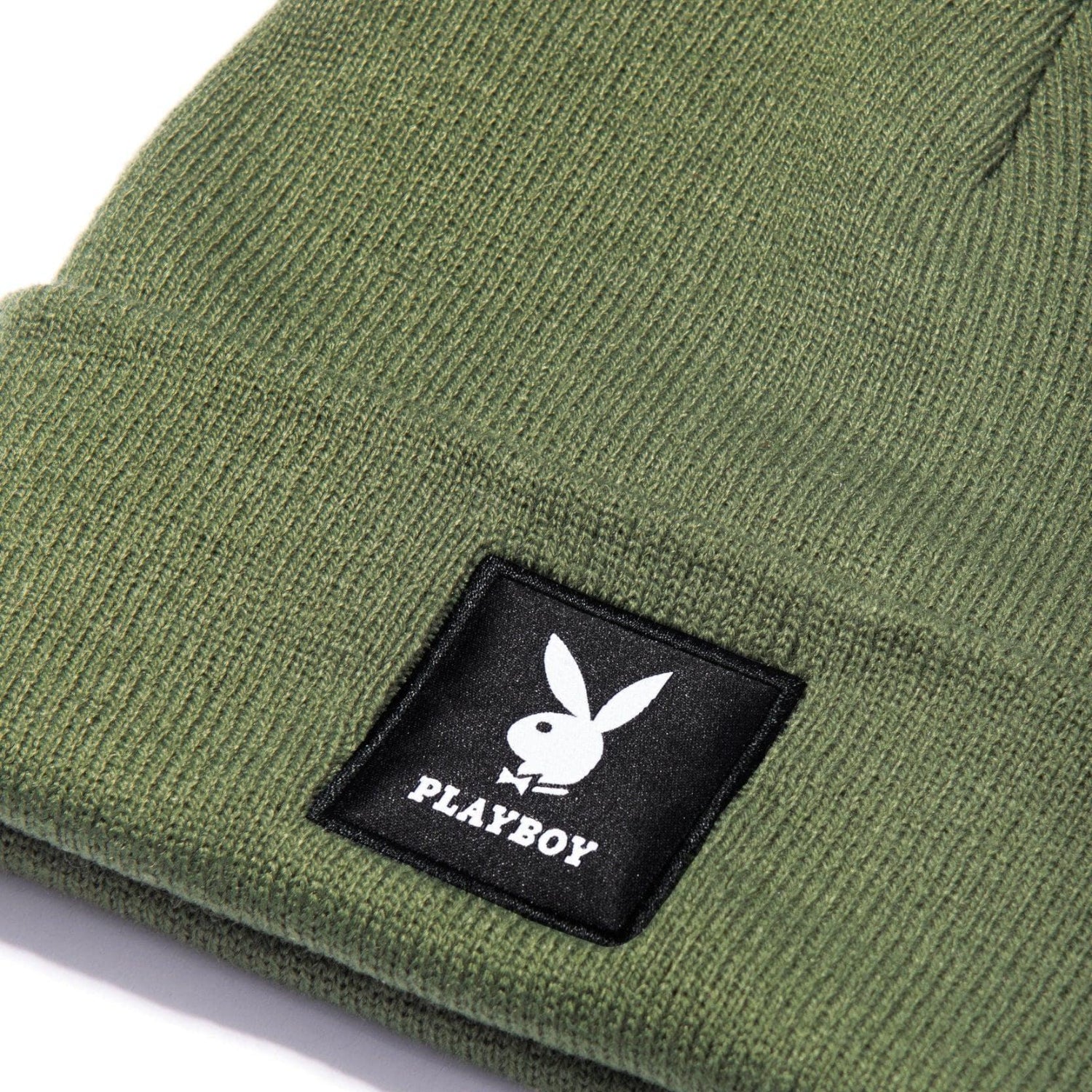 Olive green knit beanie with black patch featuring white bunny logo and text.