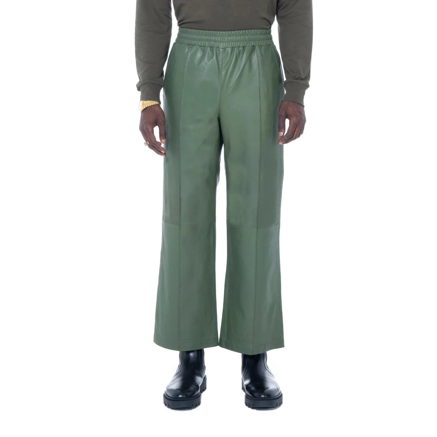 Green leather flare pants for men, styled with black boots and a dark long sleeve shirt.