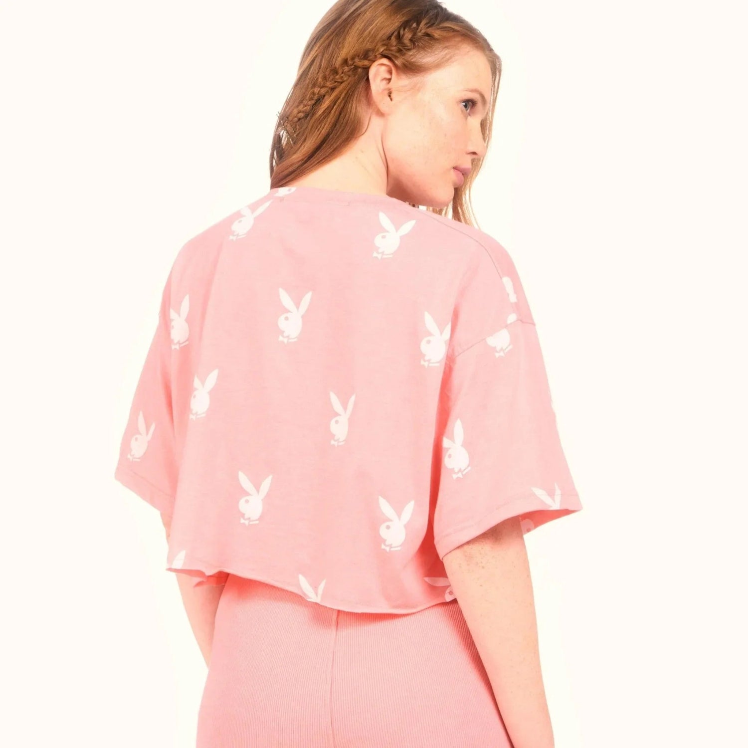 Woman wearing pink cropped t-shirt with white bunny logo pattern, casual style