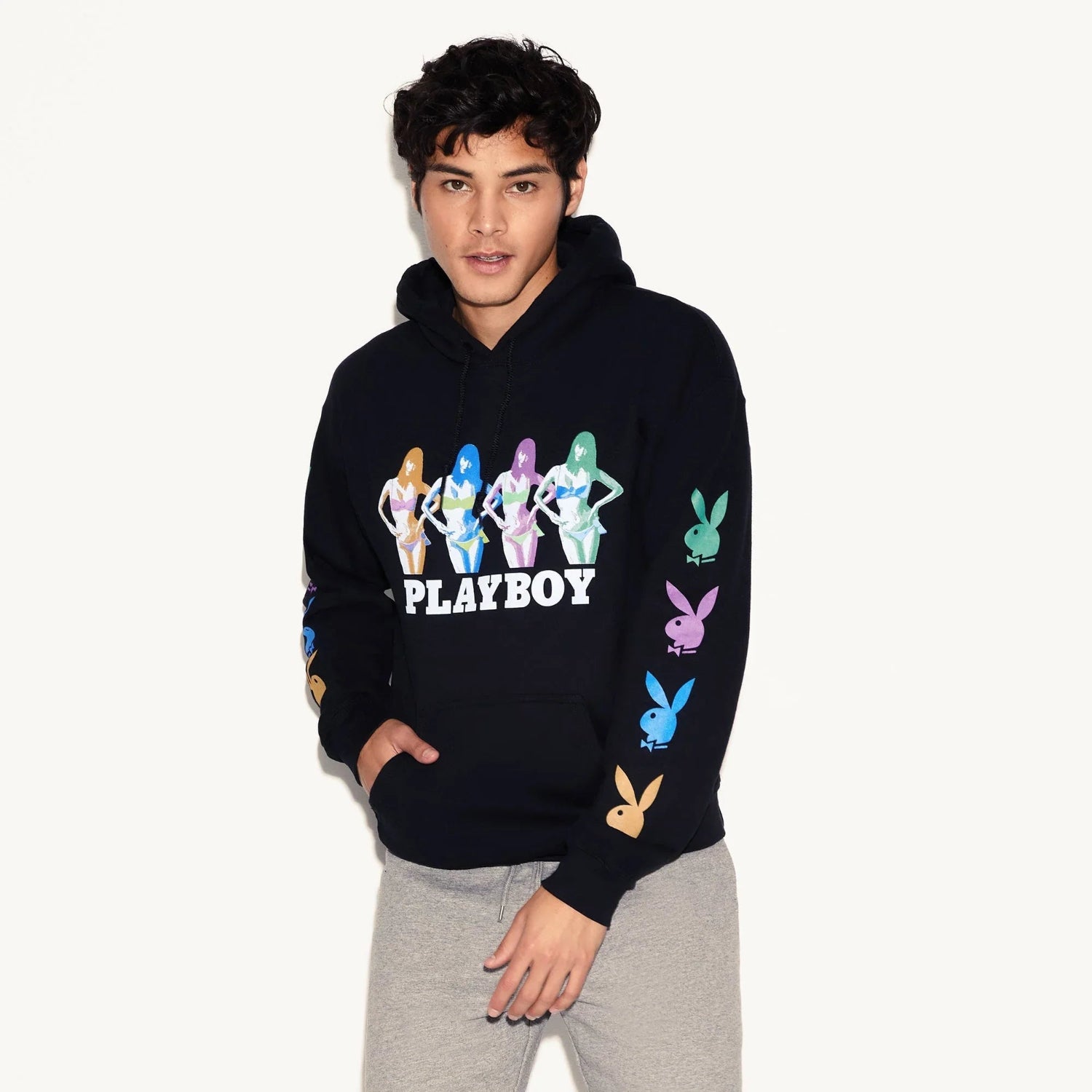 Man wearing a black hoodie with colorful bunny icons and illustrated figures, casual fashion.
