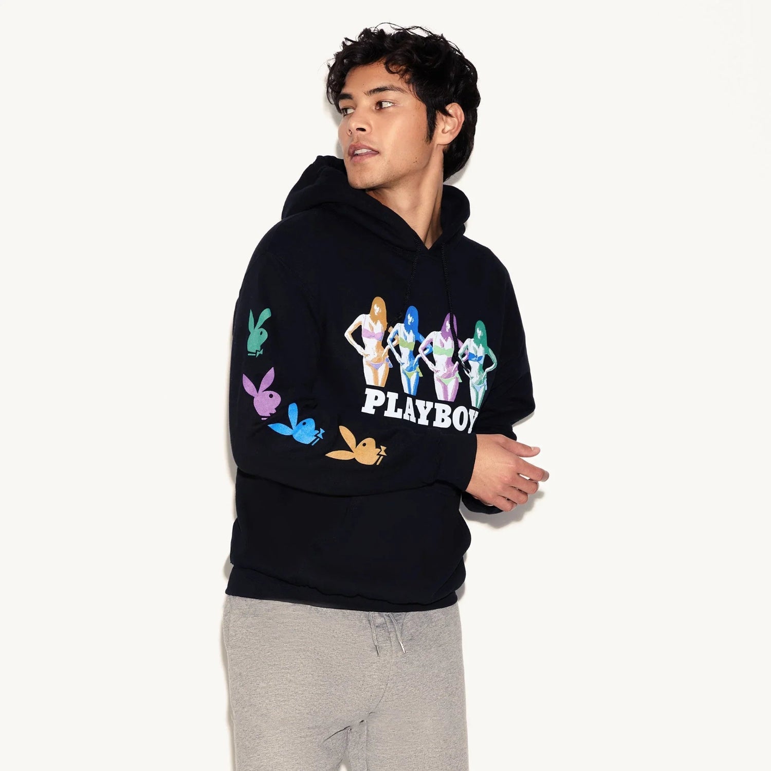 Man wearing black hoodie with colorful graphic bunnies and Playboy logo, grey sweatpants