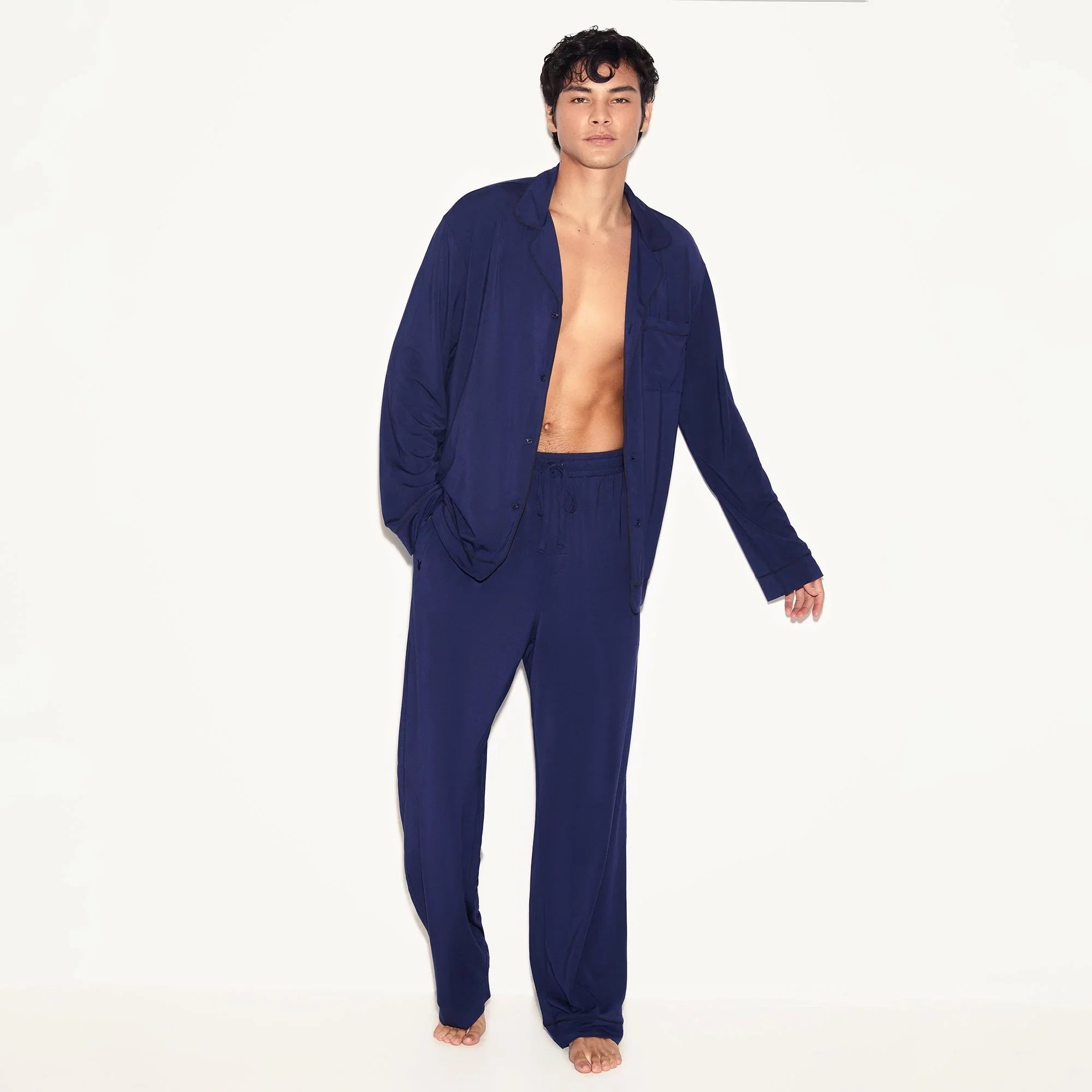 Man wearing classic navy blue men's sleepwear set with button-up shirt and drawstring pants