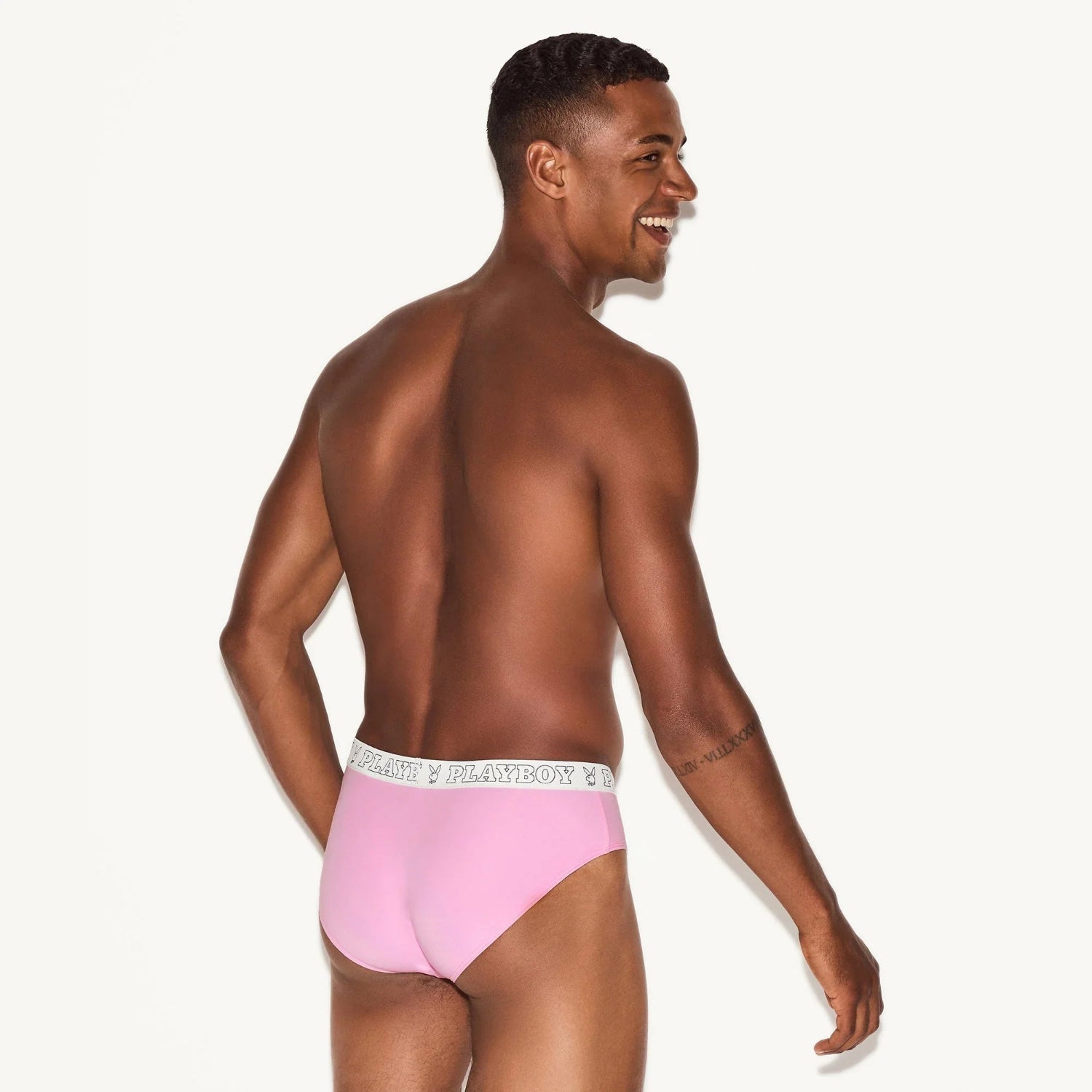 Man modeling pink men's modal briefs with logo waistband on a plain background