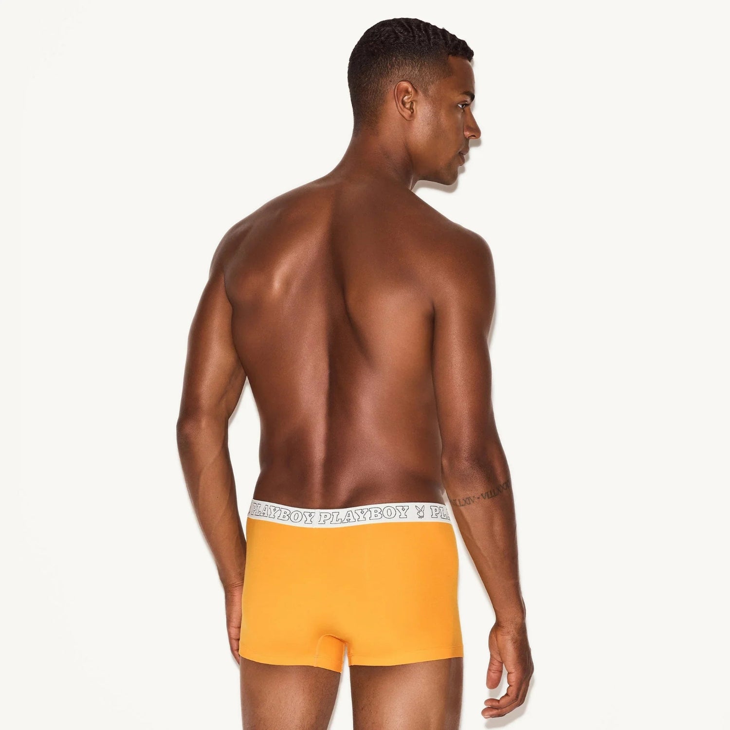 Man modeling orange men's modal trunks with white elastic waistband, rear view