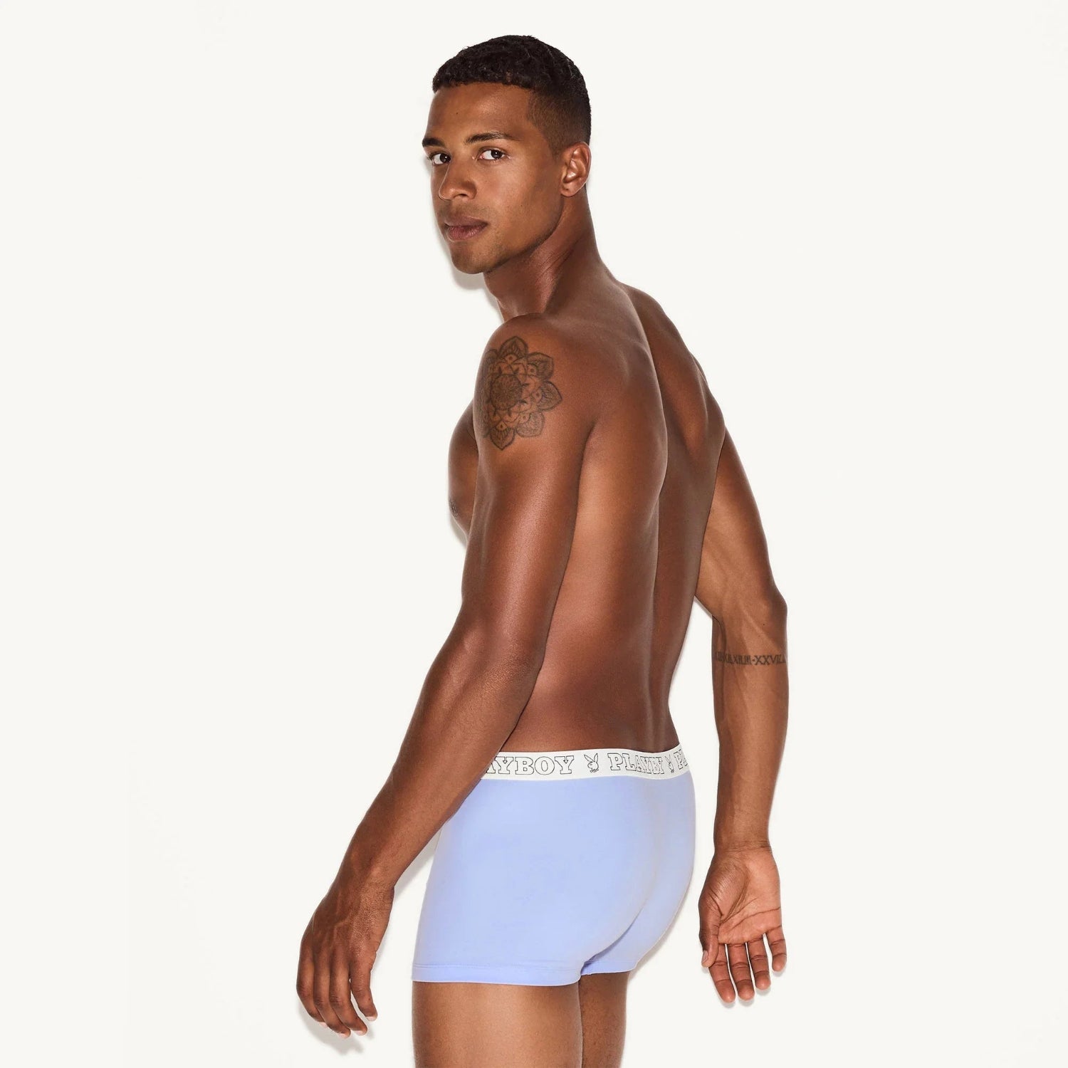 Male model wearing light blue modal trunk underwear with logo waistband, tattoo on shoulder