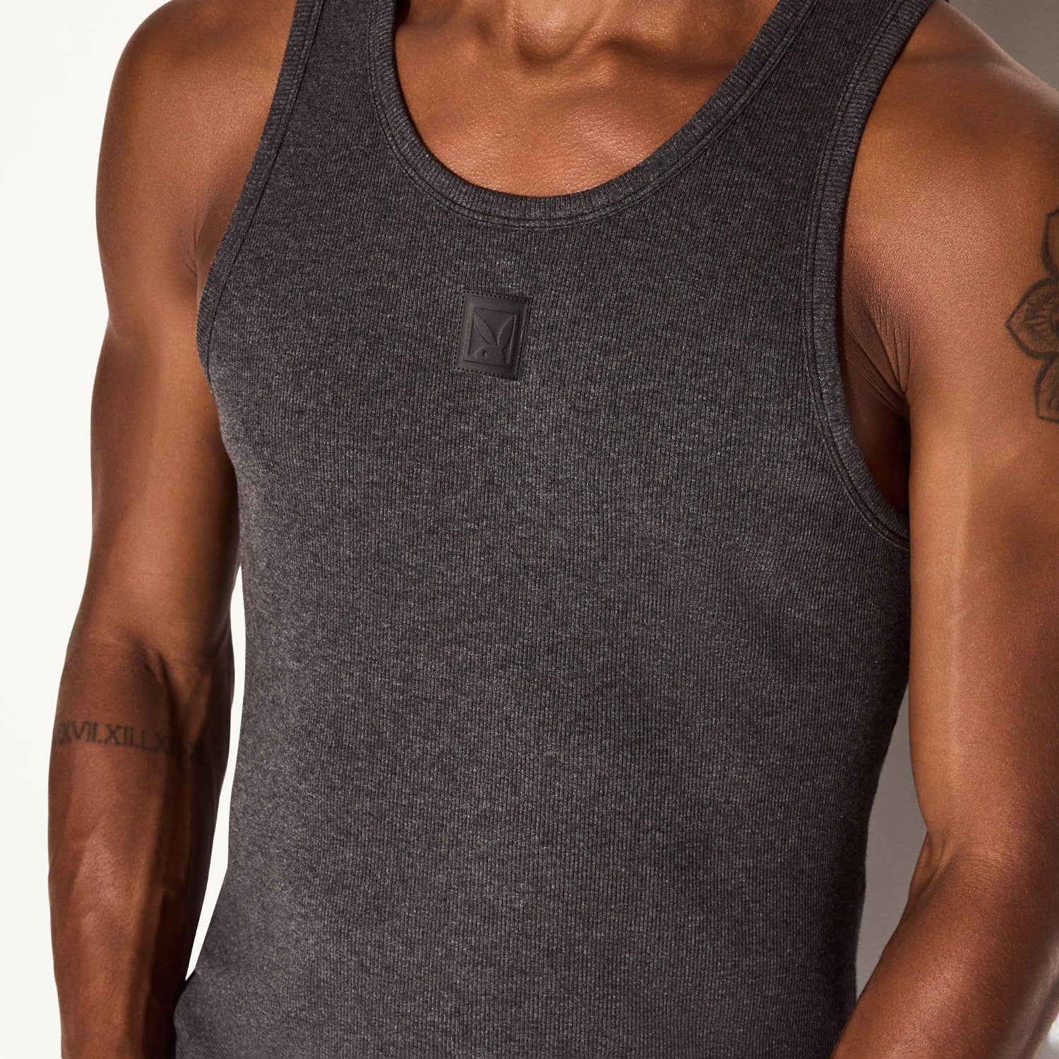 Men's charcoal ribbed tank top with patch detail, close-up torso view
